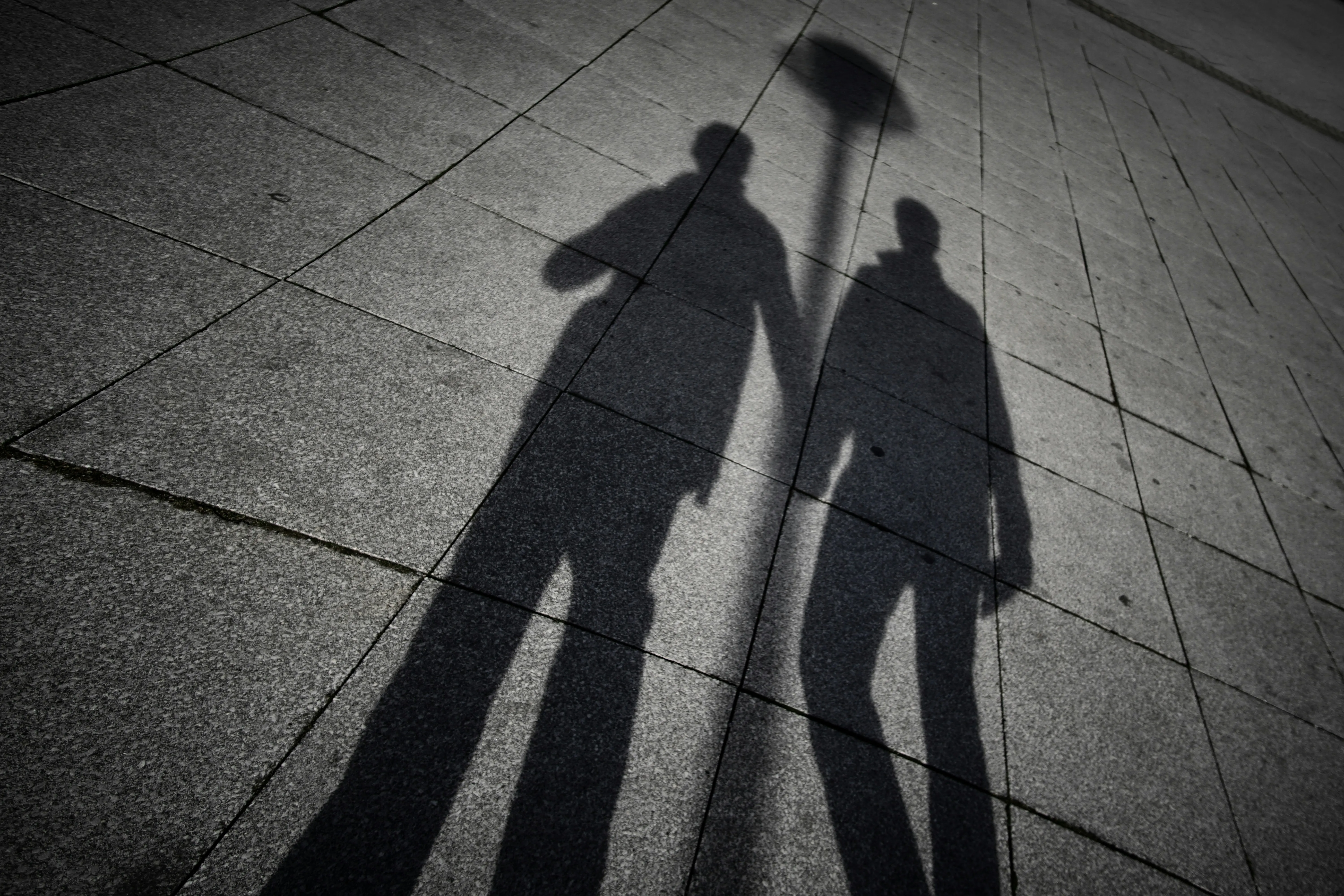 A black and white silhouette of the shadows of two men on a pavement to show how same-sex couples adoption India is a possibility, leading to a rise in queer parenting in India and inclusivity and queer families despite hurdles