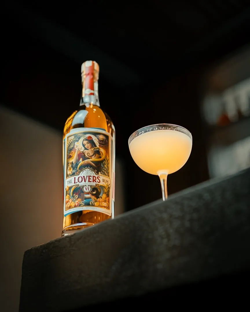 A picture of a bottle of The Lovers Rum with a glass with a cocktail in it, to show how craft rum India has led to the popularity of using rum for cocktails India as well.