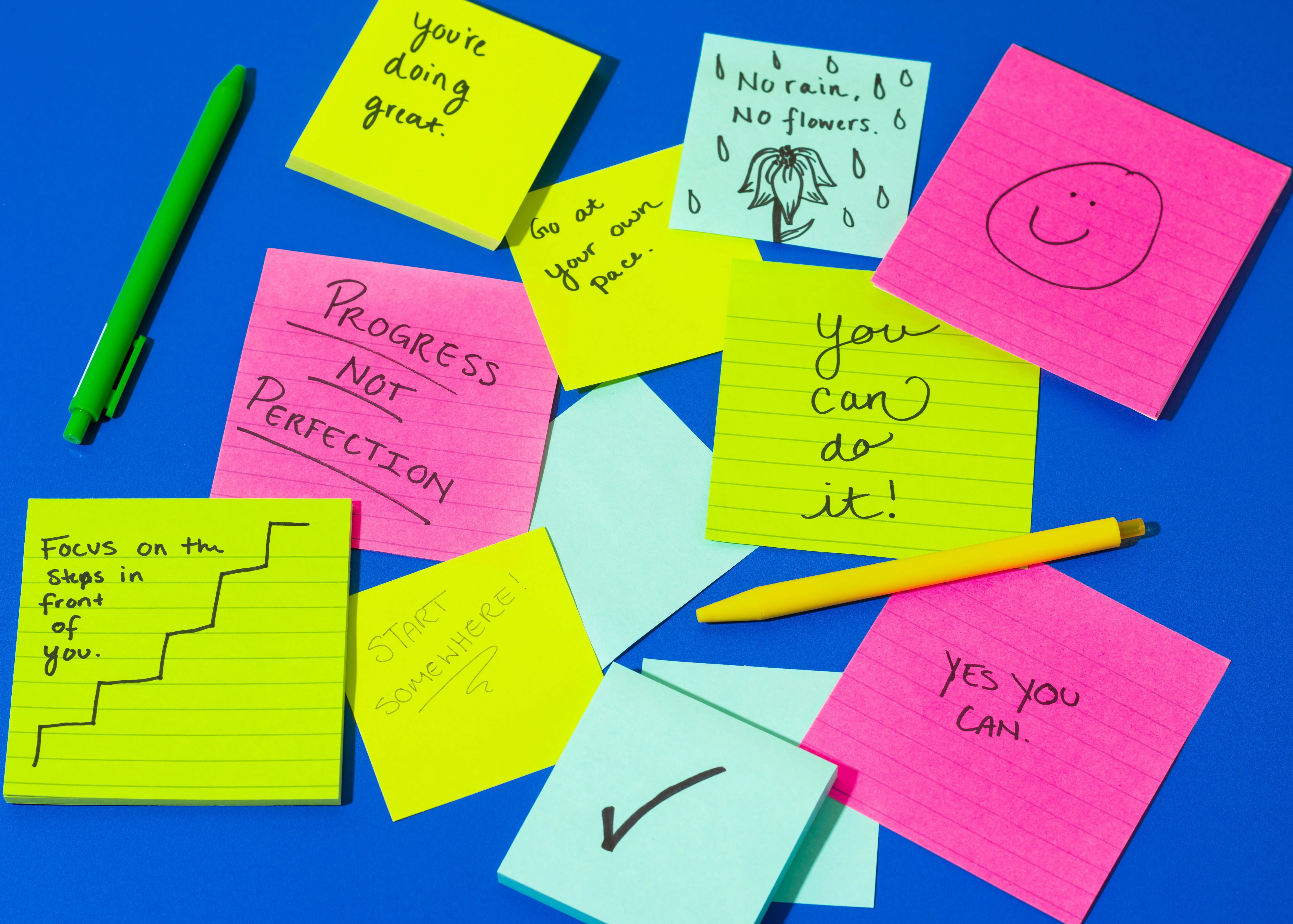 A blue board with sticky notes in pink and green colour
