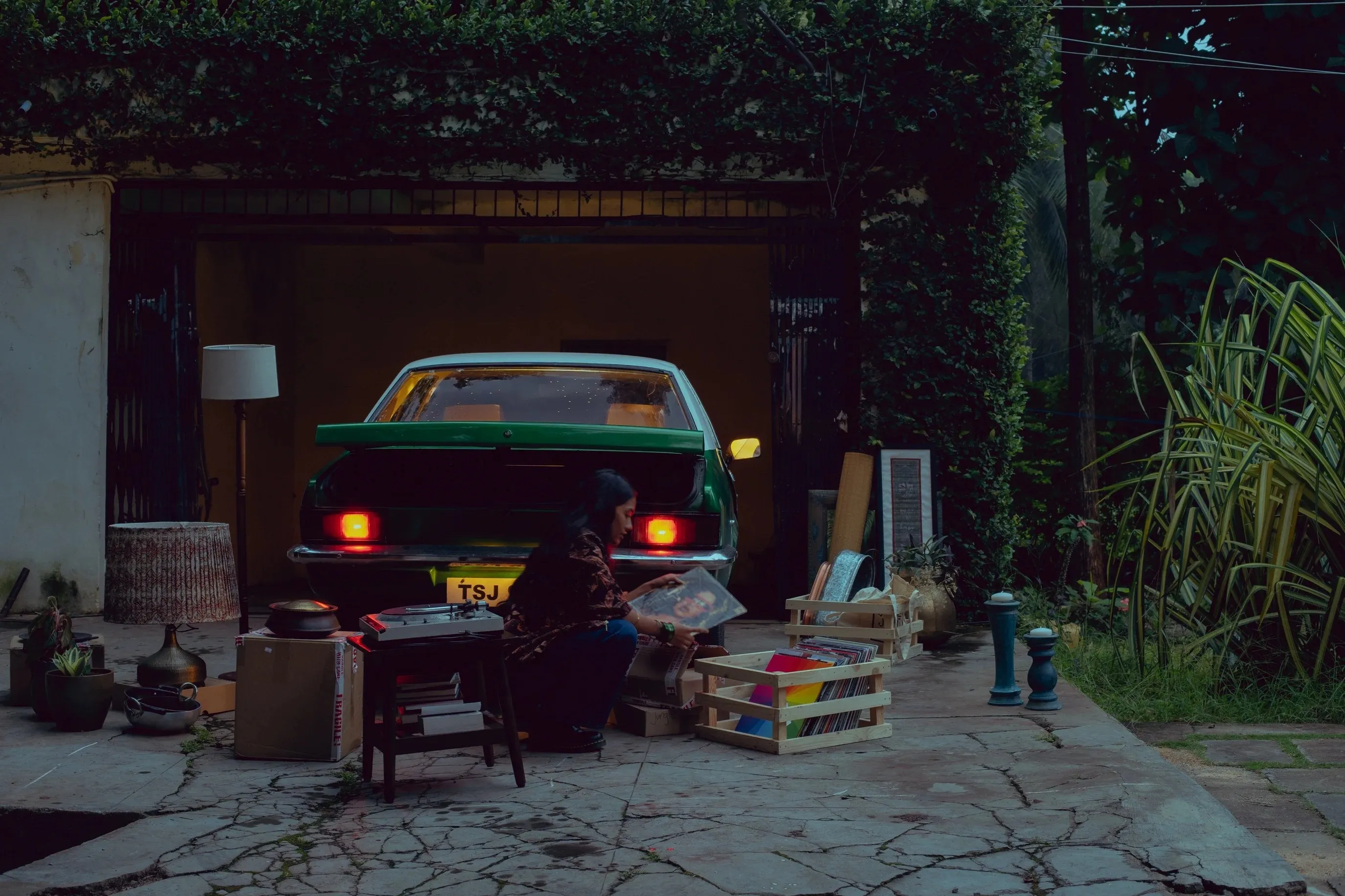 A woman sits and sifts through her belongings, including a couple of vinyl record in her garage to show how vinyl records in India are gaining popularity as people turn to nostalgia for comfort.com