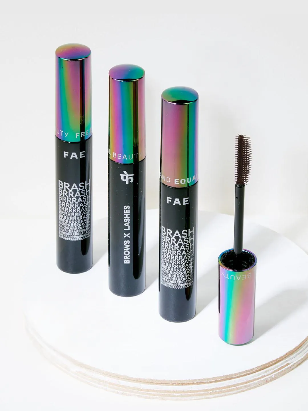 Three eyebrow mascaras placed vertically next to one another on a marble trinket tray