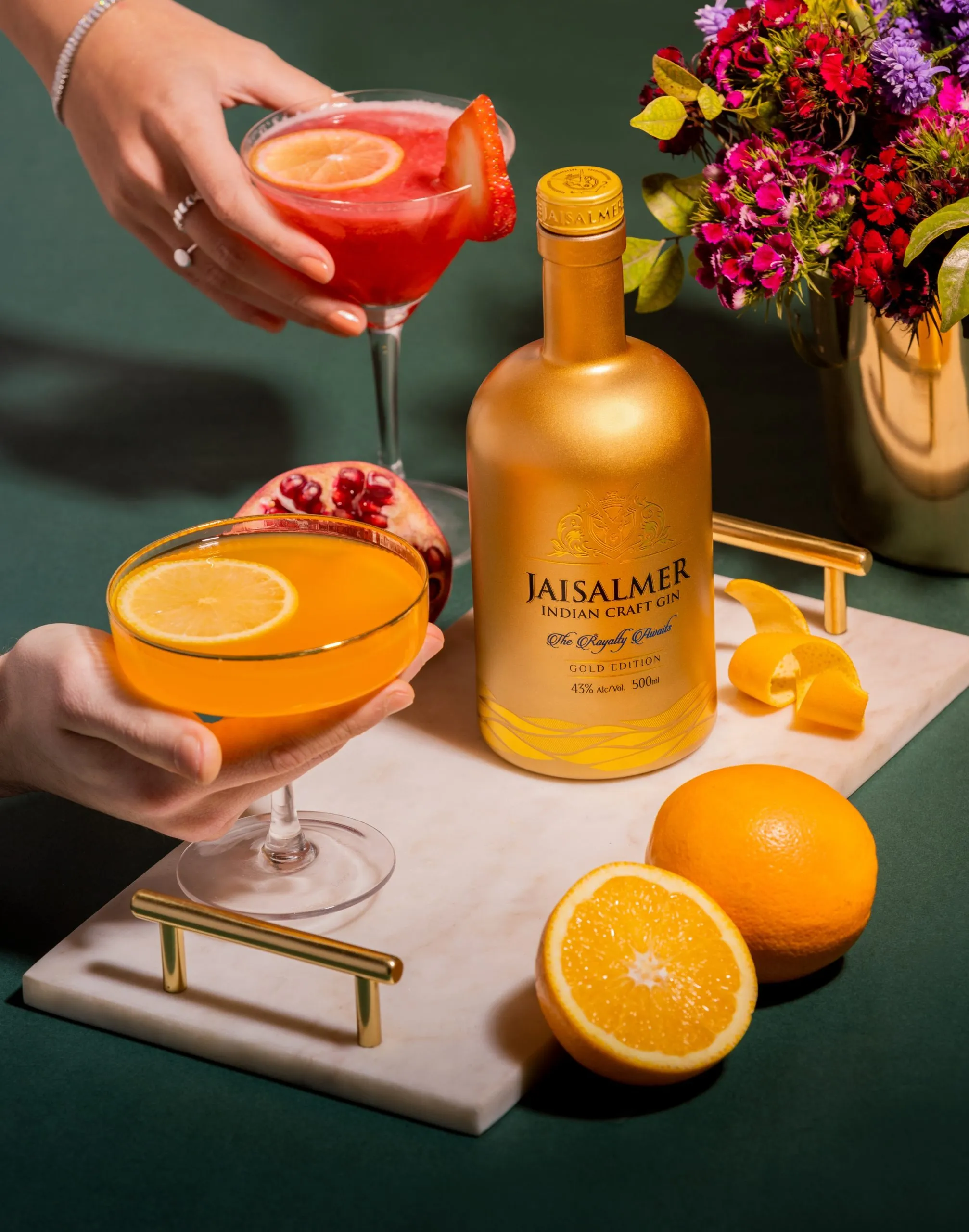 A bottle of Golden Jaisalmer Indian Craft Gin with two cocktails and pomelo to show how Indian craft gins can be enjoyed at home, given the extra touch thanks to Indian botanical gins and access to premium Indian gin