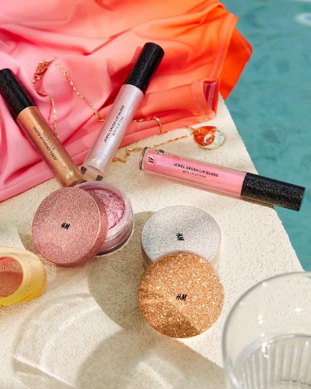 Highlighter powder from H&M placed by the poolside with lipglosses
