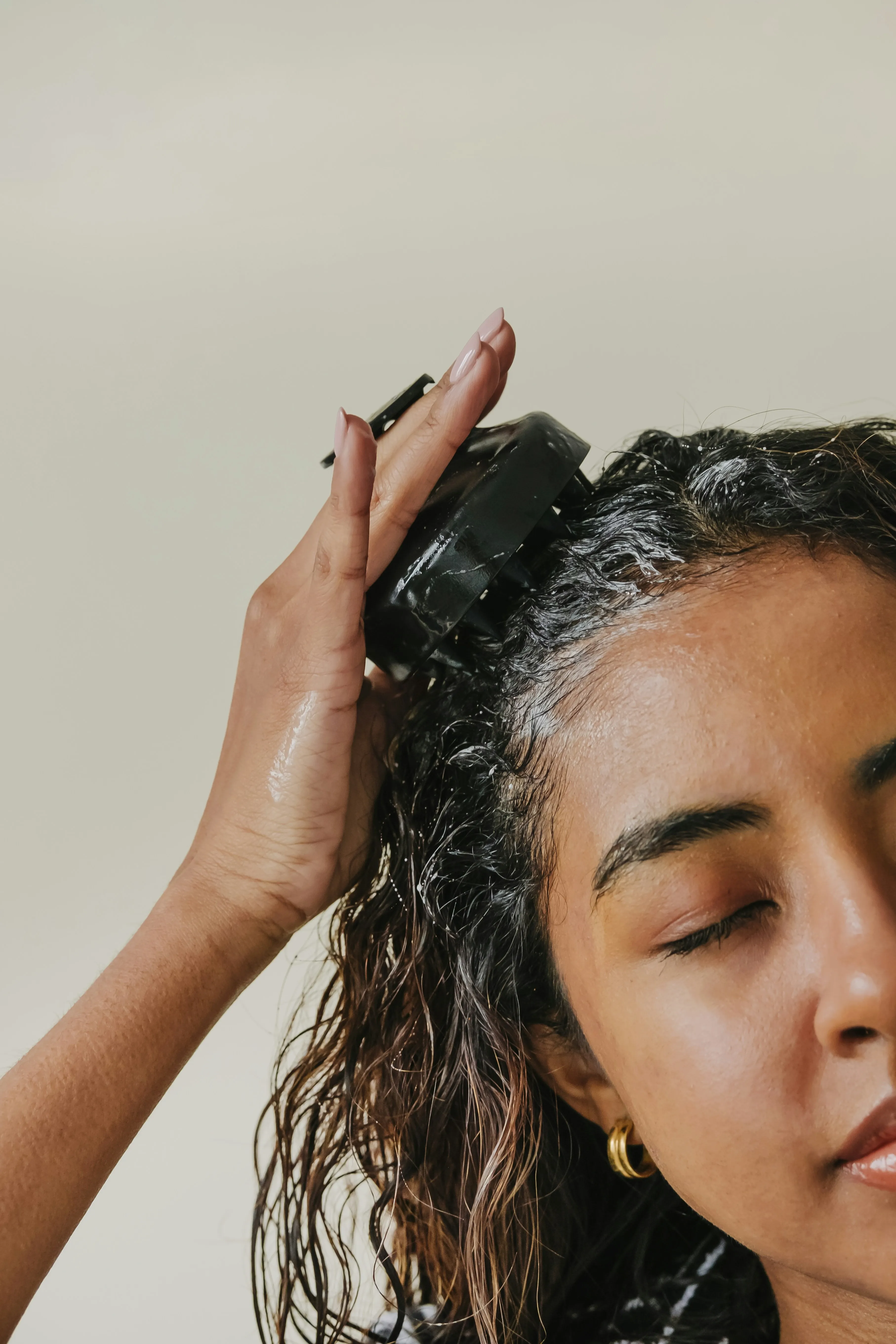 A woman deep cleansing her scalp with shampoo and other hair growth products