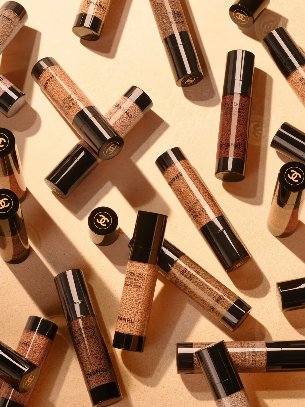 A few bottles of Chanel Les Beiges skin tint placed on a flesh-toned backdrop