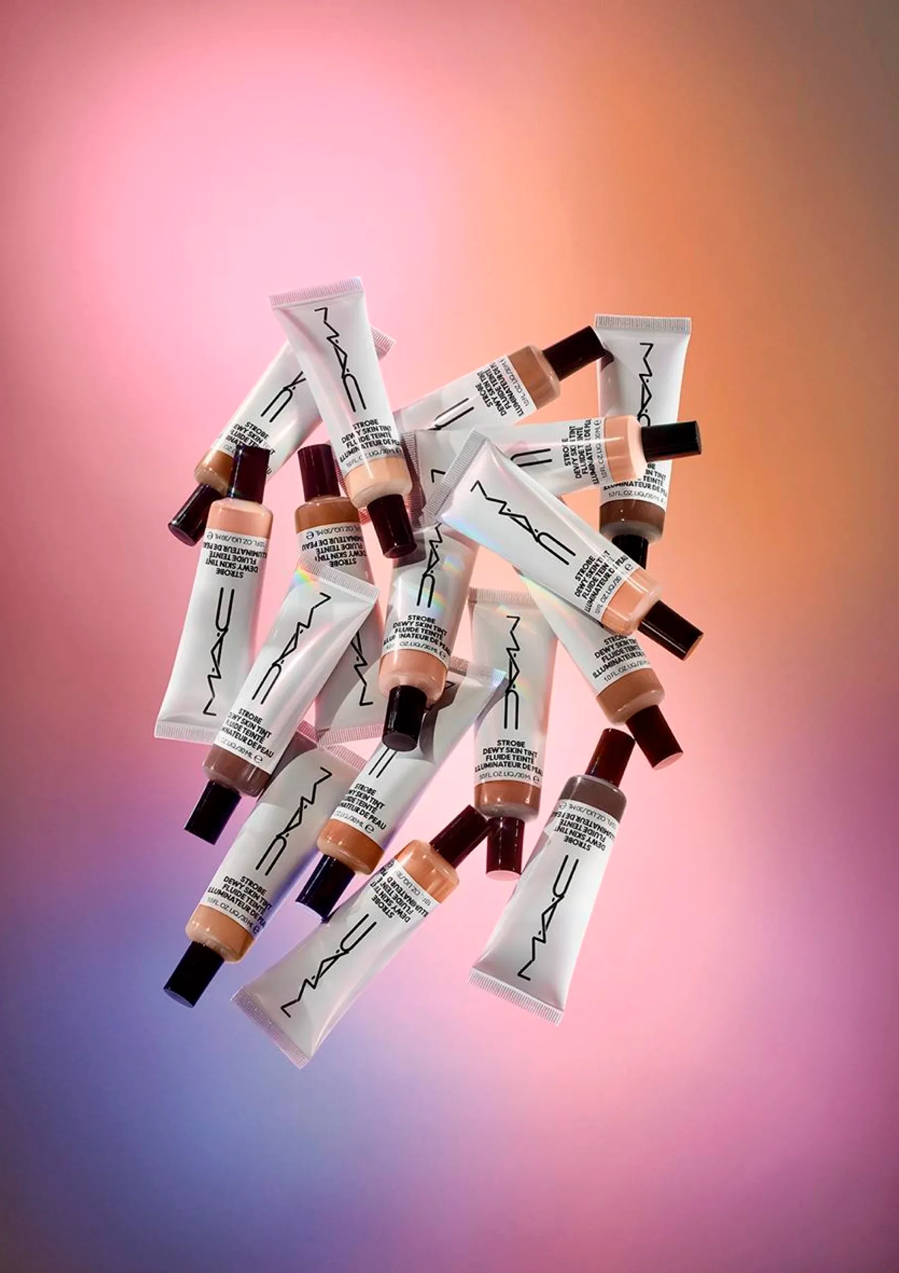 A bunch of M.A.C skin tint tubes placed together against a colourful backdrop