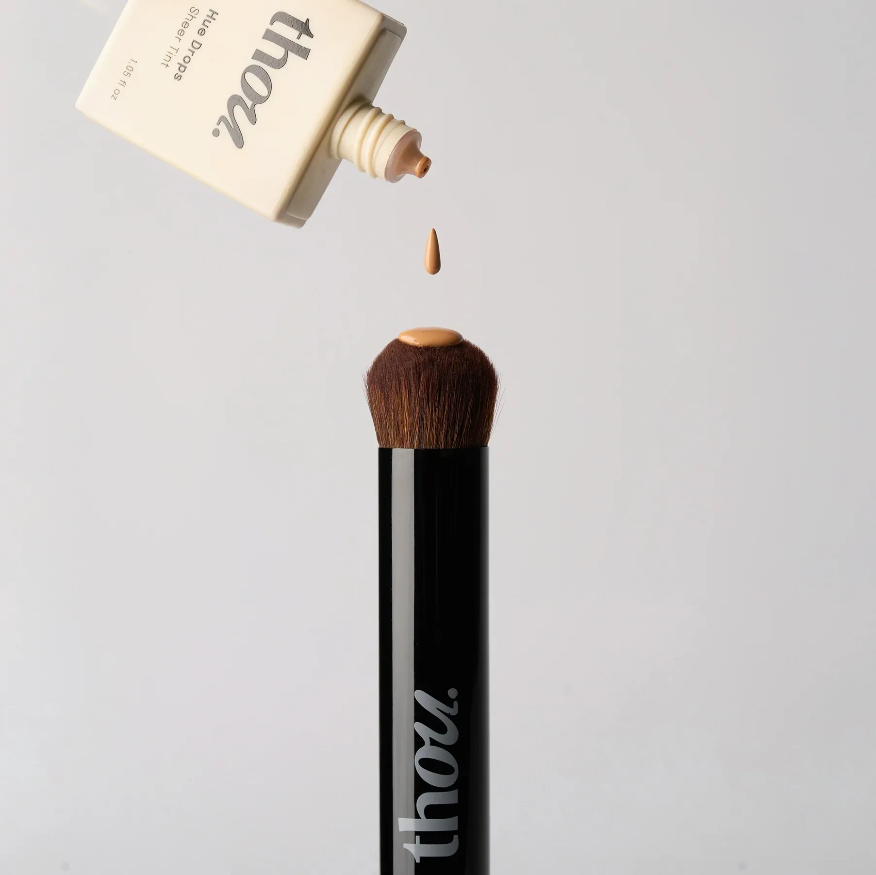 Skin tint from Thou Beauty's bottle pouring out on a brush