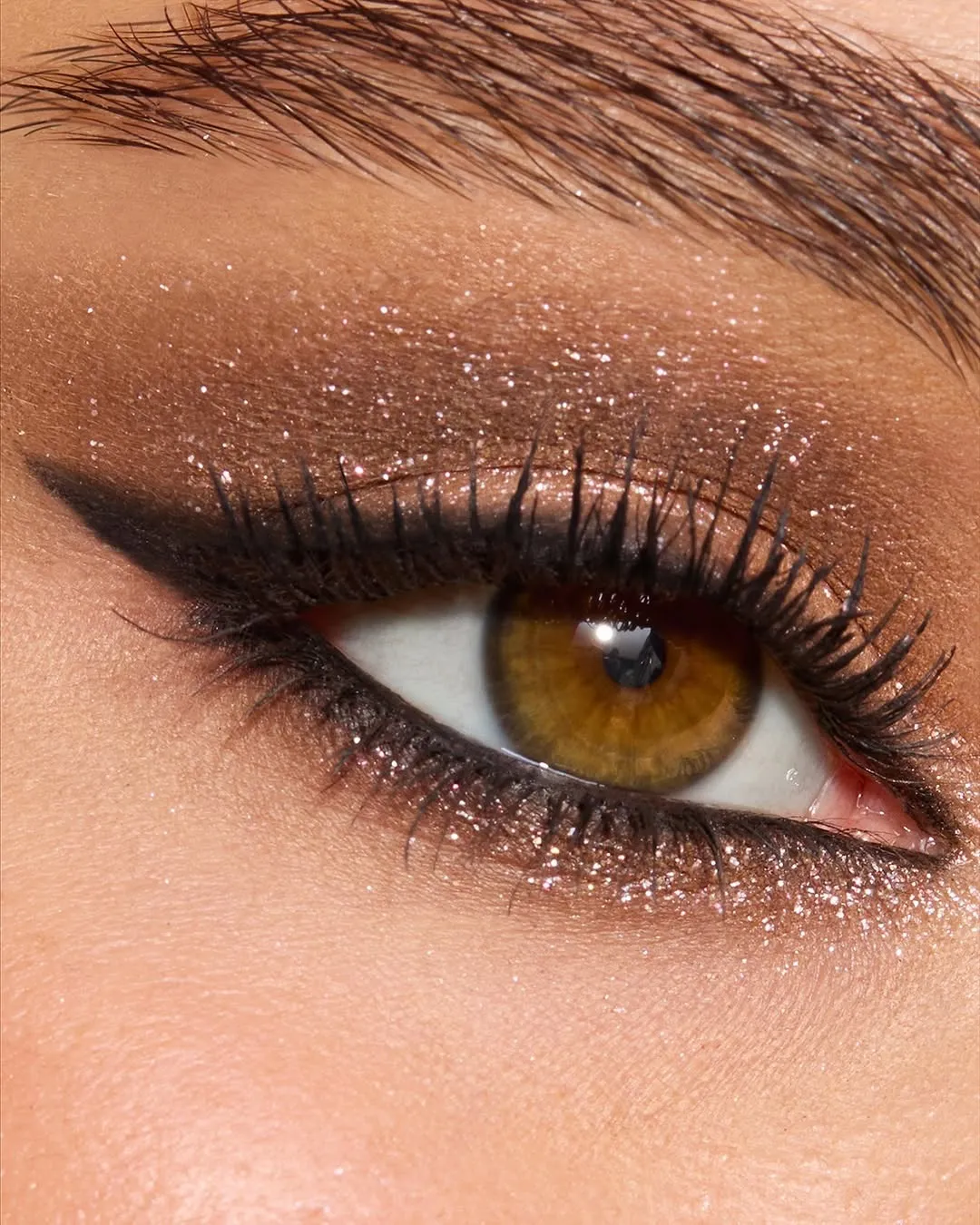 A zoomed-in shot of bridal make-up for the eyes with matte and metallic eyeshadow, winged eyeliner and fluttery lashes.