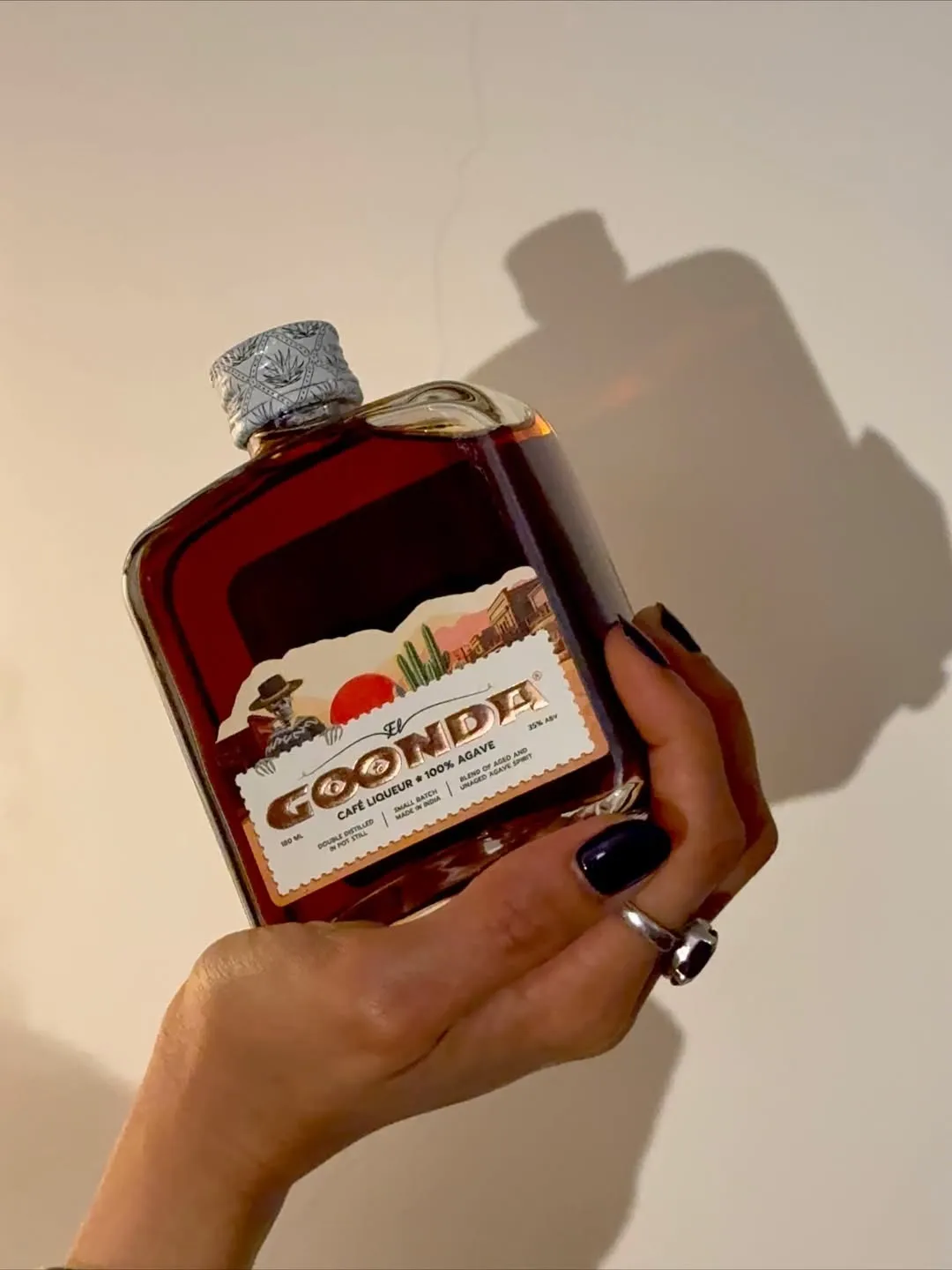 A picture of  a person holding a bottle of Goonda, one of the agave spirits in India that's considered one of the more popular Indian agave spirits competing with the best tequila in India