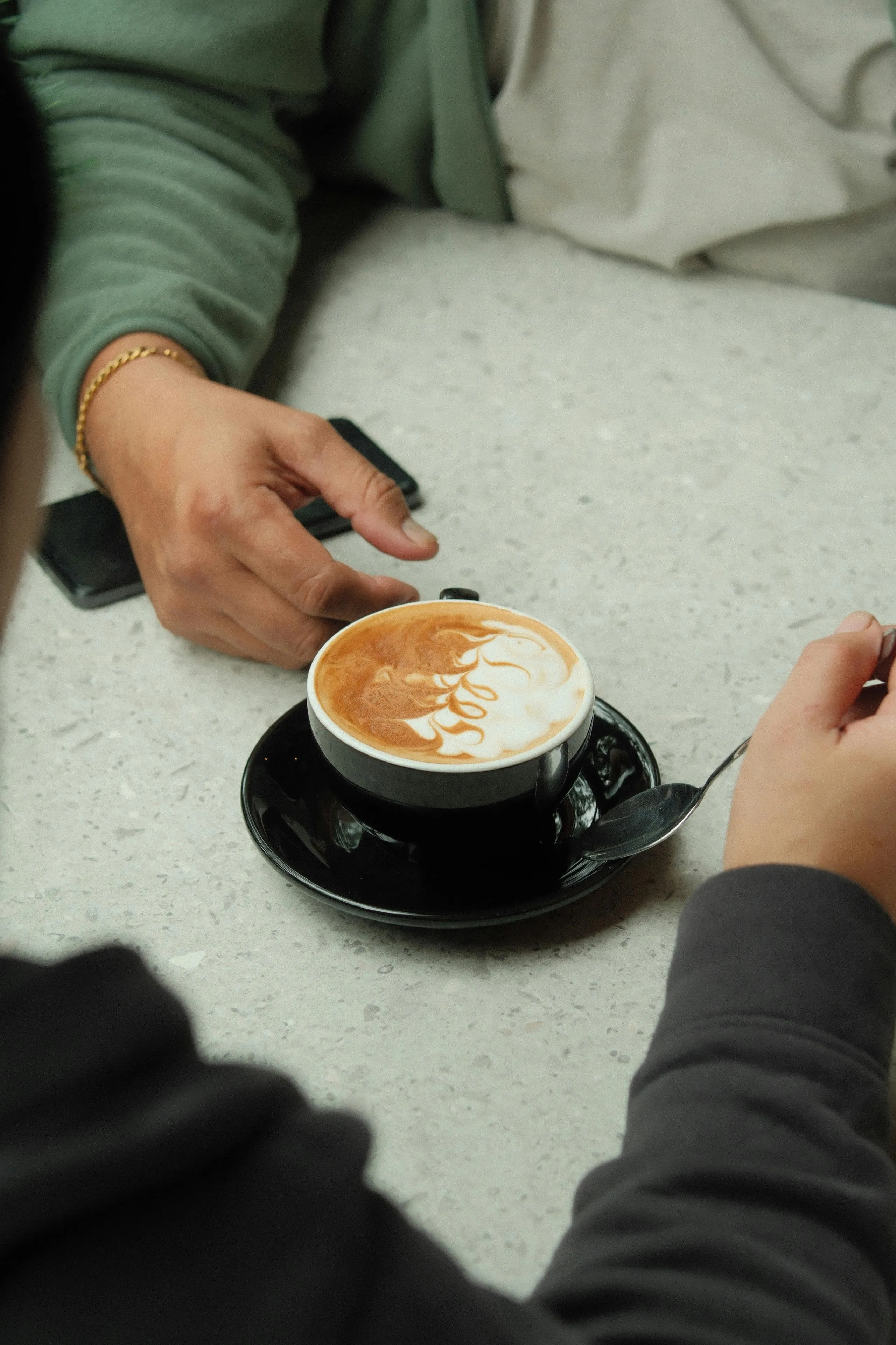 A picture of two people reaching for the same cup of coffee to show how flirting culture in India and consent and flirting is still impacted by patriarchal norms.