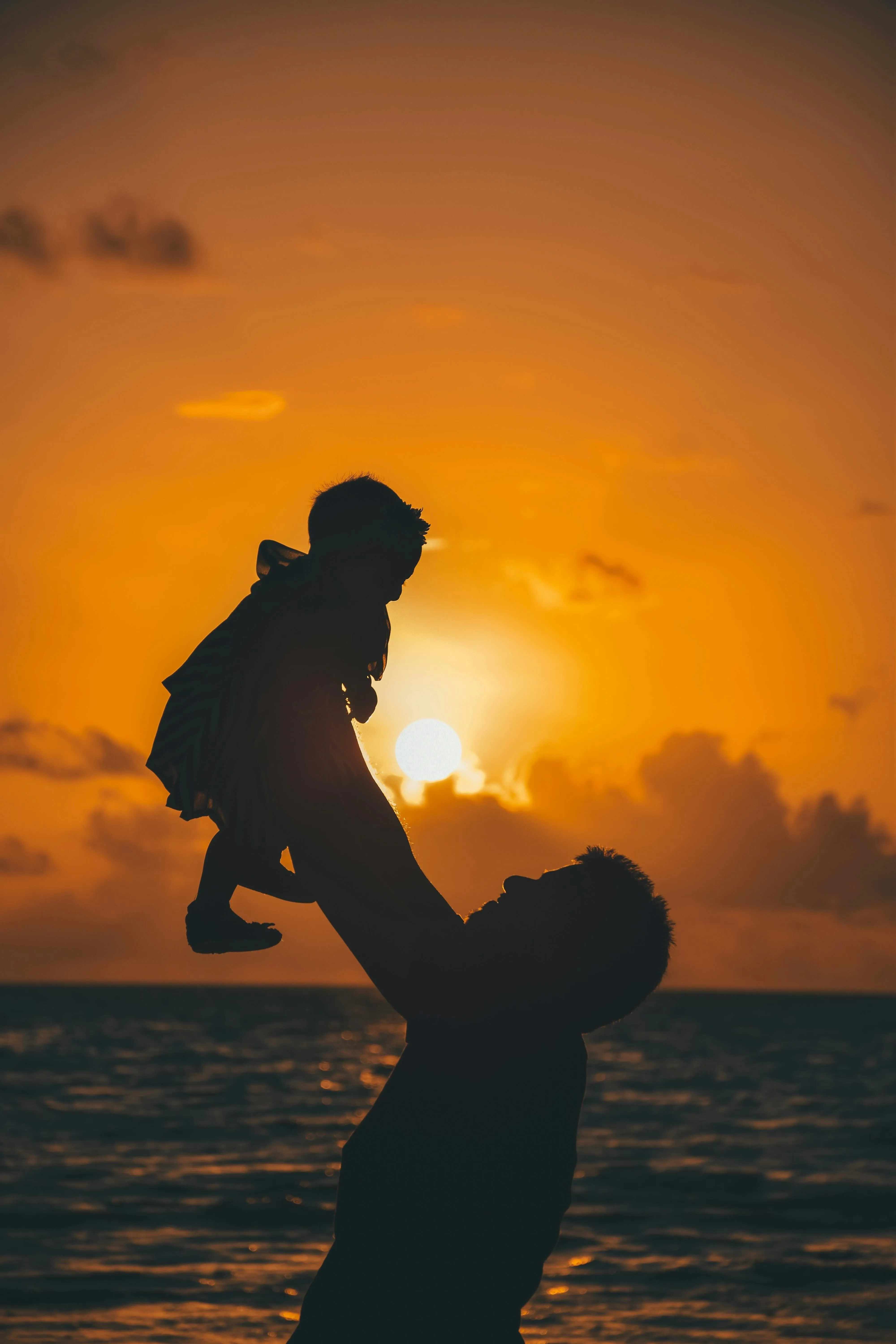 A picture of a father and his little son outdoors against the sunset