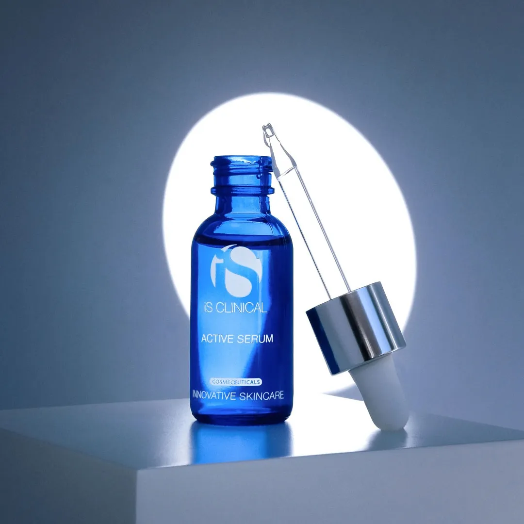 A blue bottle of iS Clinical Active Serum placed against a spotlight