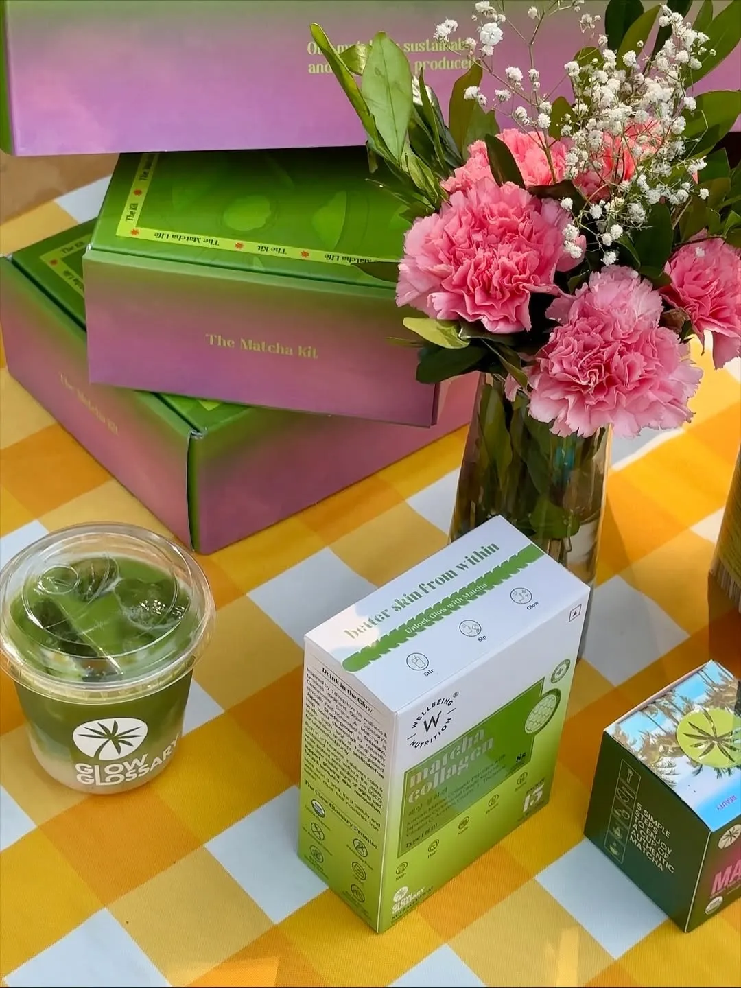 Glow Glassy matcha packets placed on a table with a yellow and white gingham table cloth