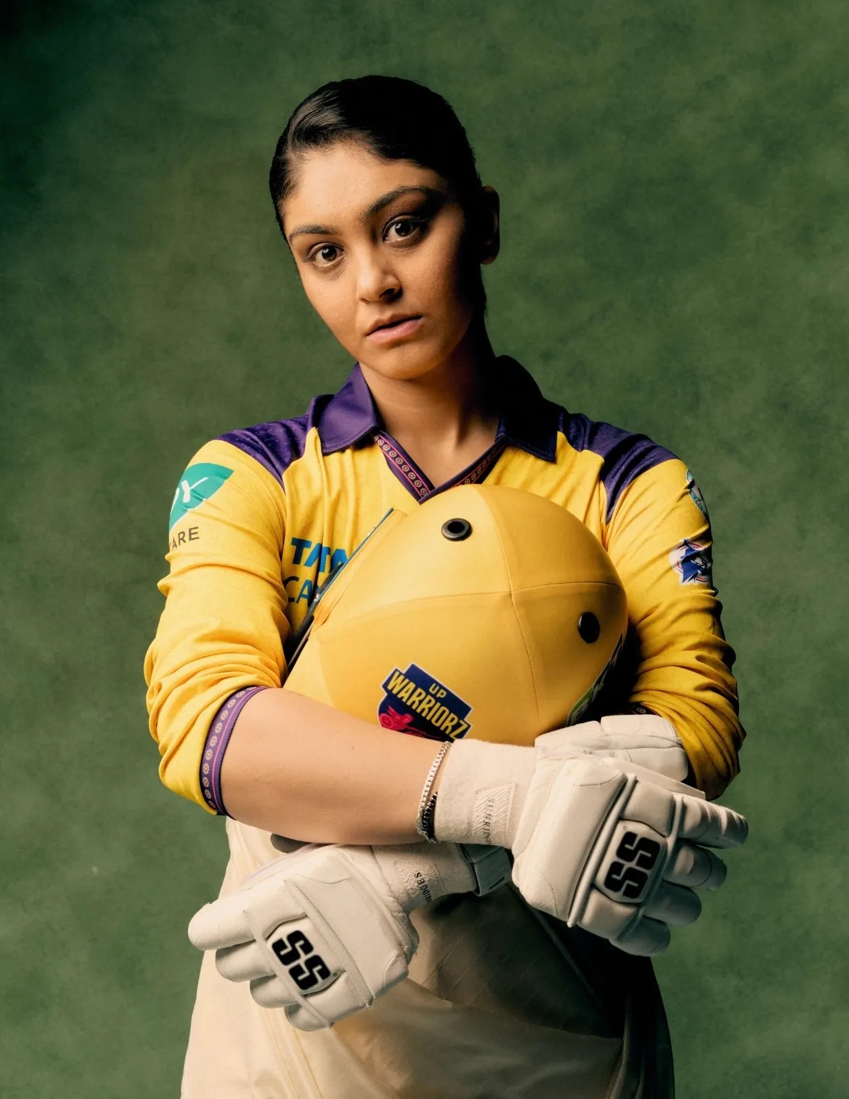 UP Warriorz player in yellow cricket jersey holding helmet, highlighting women&rsquo;s cricket identity and uniform design