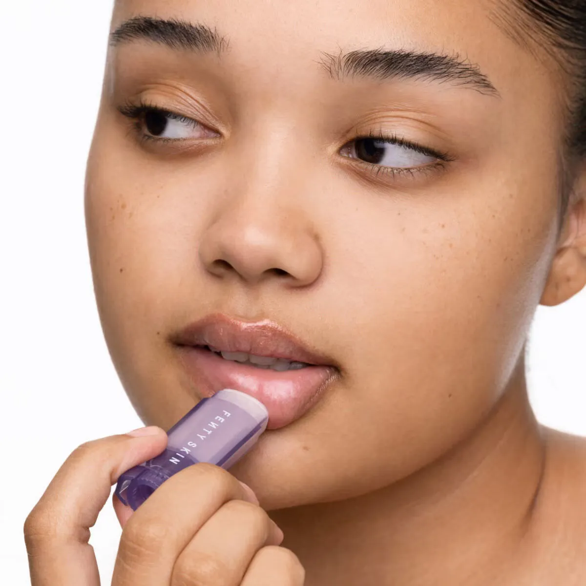 A woman applying Fenty lip balm for soft lips