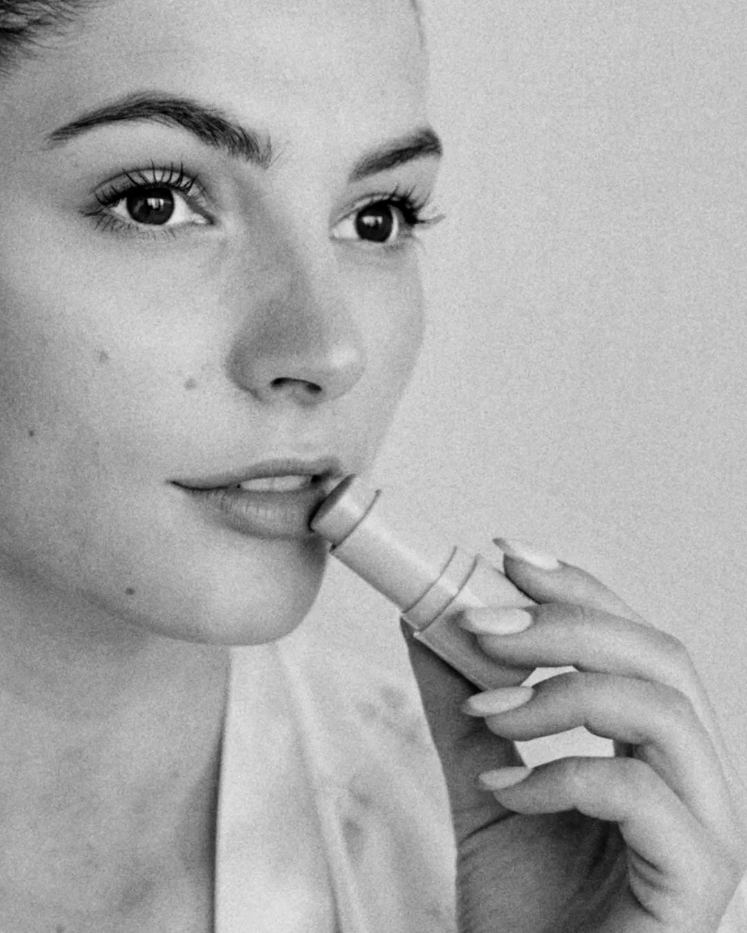 A black and white photo of a woman applying the best lip balm in india