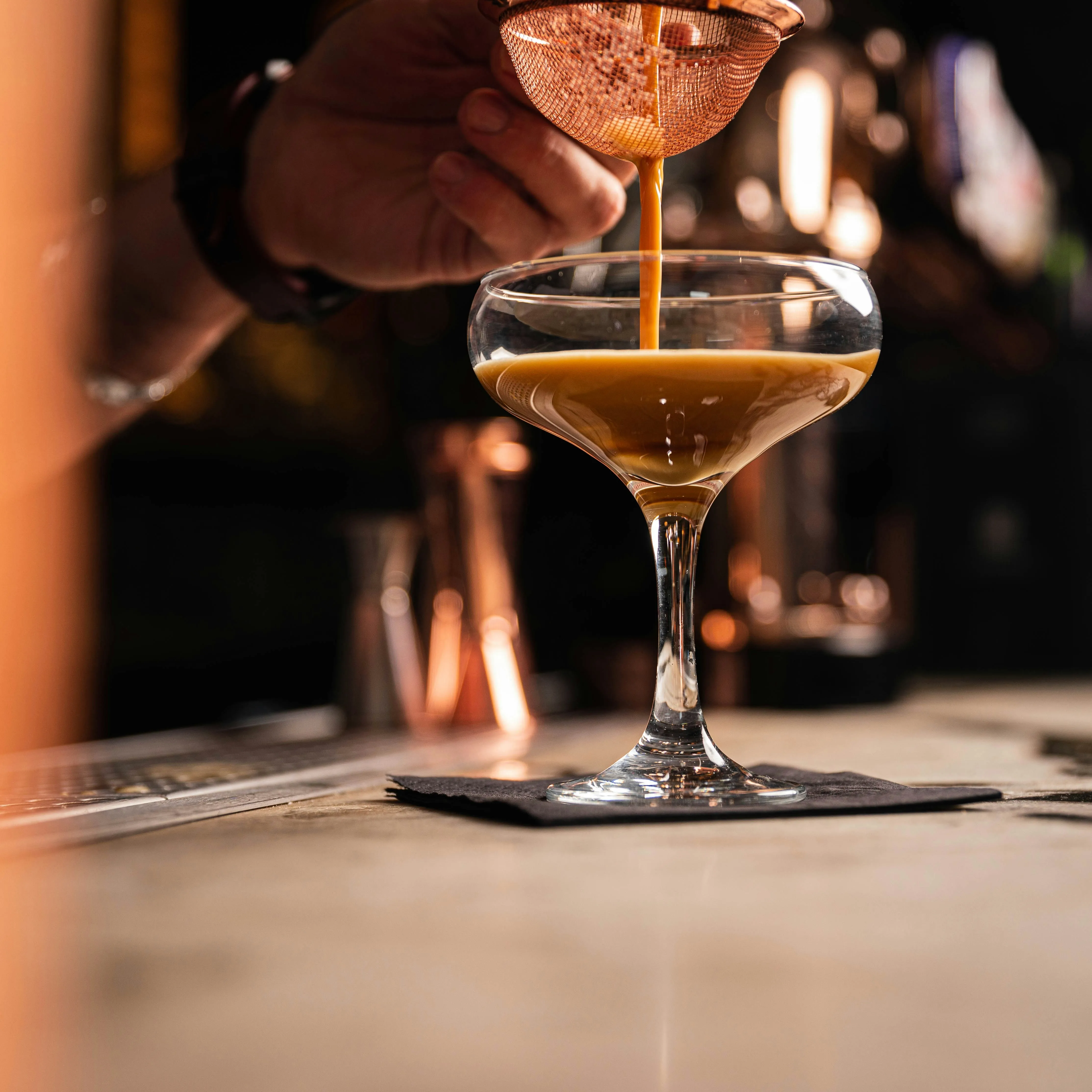 A picture of a person pouring bitters in a drink to show cocktail bitters in India are getting popular as home bar ingredients India and luxury cocktail ingredients, including non alcoholic bitters India