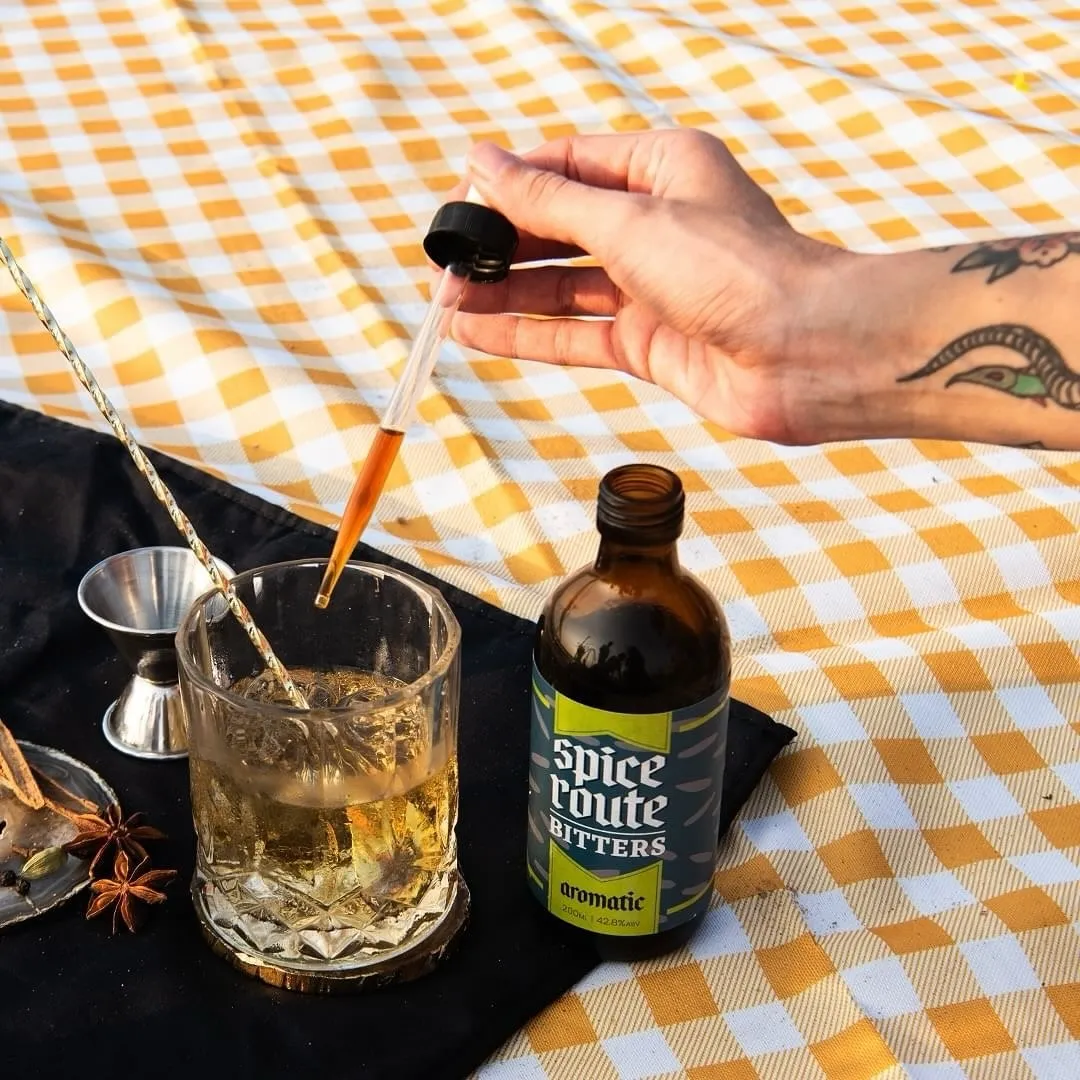 A picture of a person using a dropper to add spice route bitters to make a drink to show how cocktail bitters in India are being used as luxury cocktail ingredients, so much so that craft bitters India are being made in the country