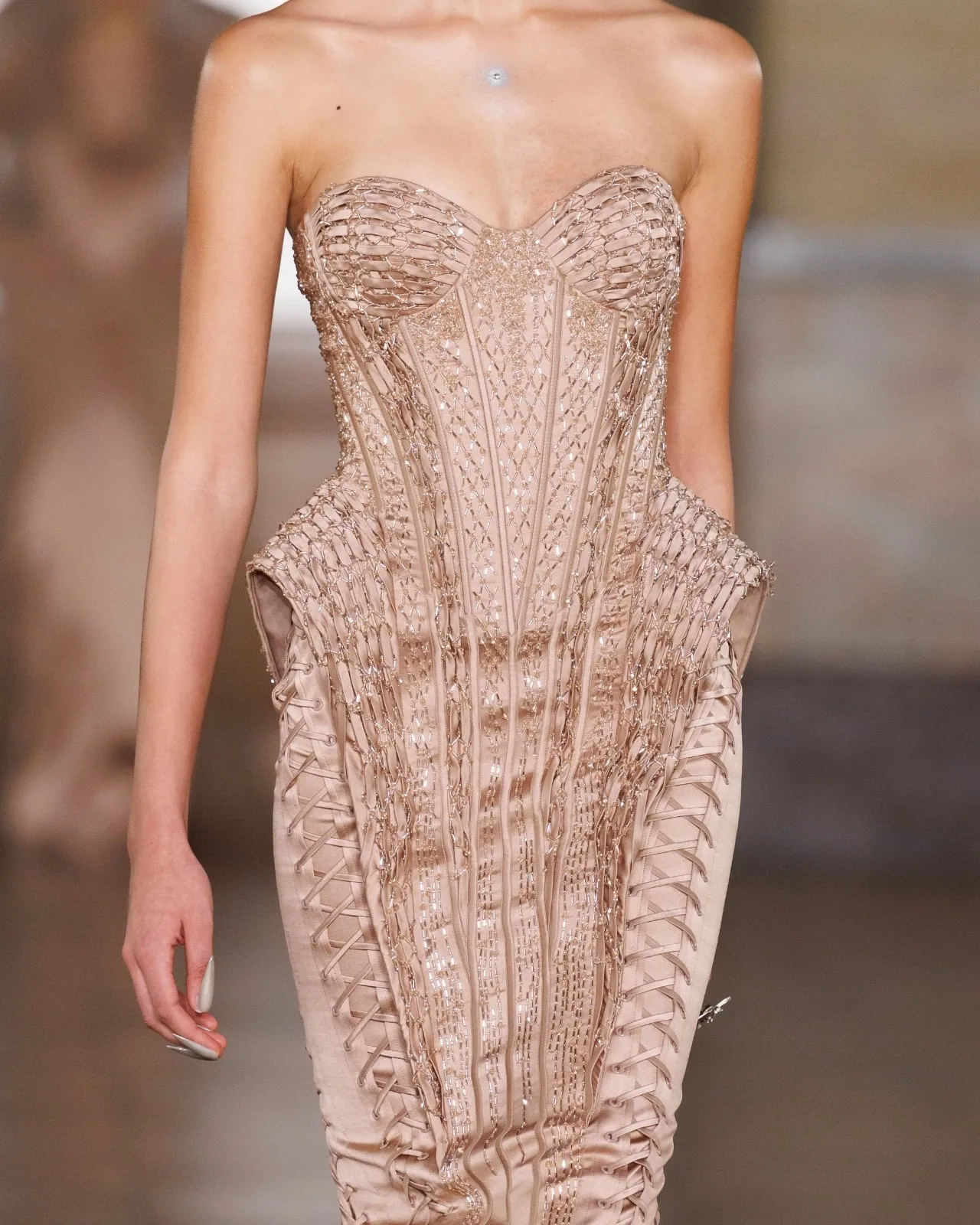 Close-up of corseted dress with exaggerated hip construction and embellished structure