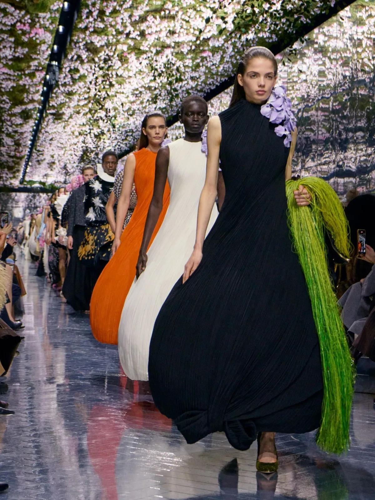 Runway models at Dior wearing gowns with exaggerated hip silhouettes demonstrating engineered body shapes in fashion