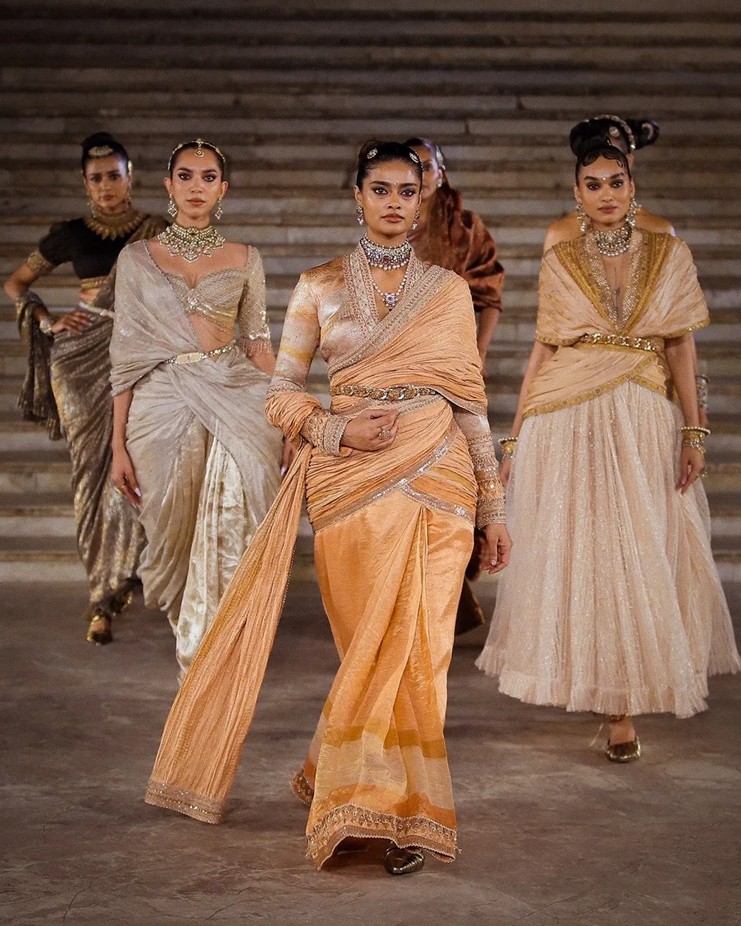 Models walking in Tarun Tahiliani couture show featuring draped silhouettes emphasising hip structure