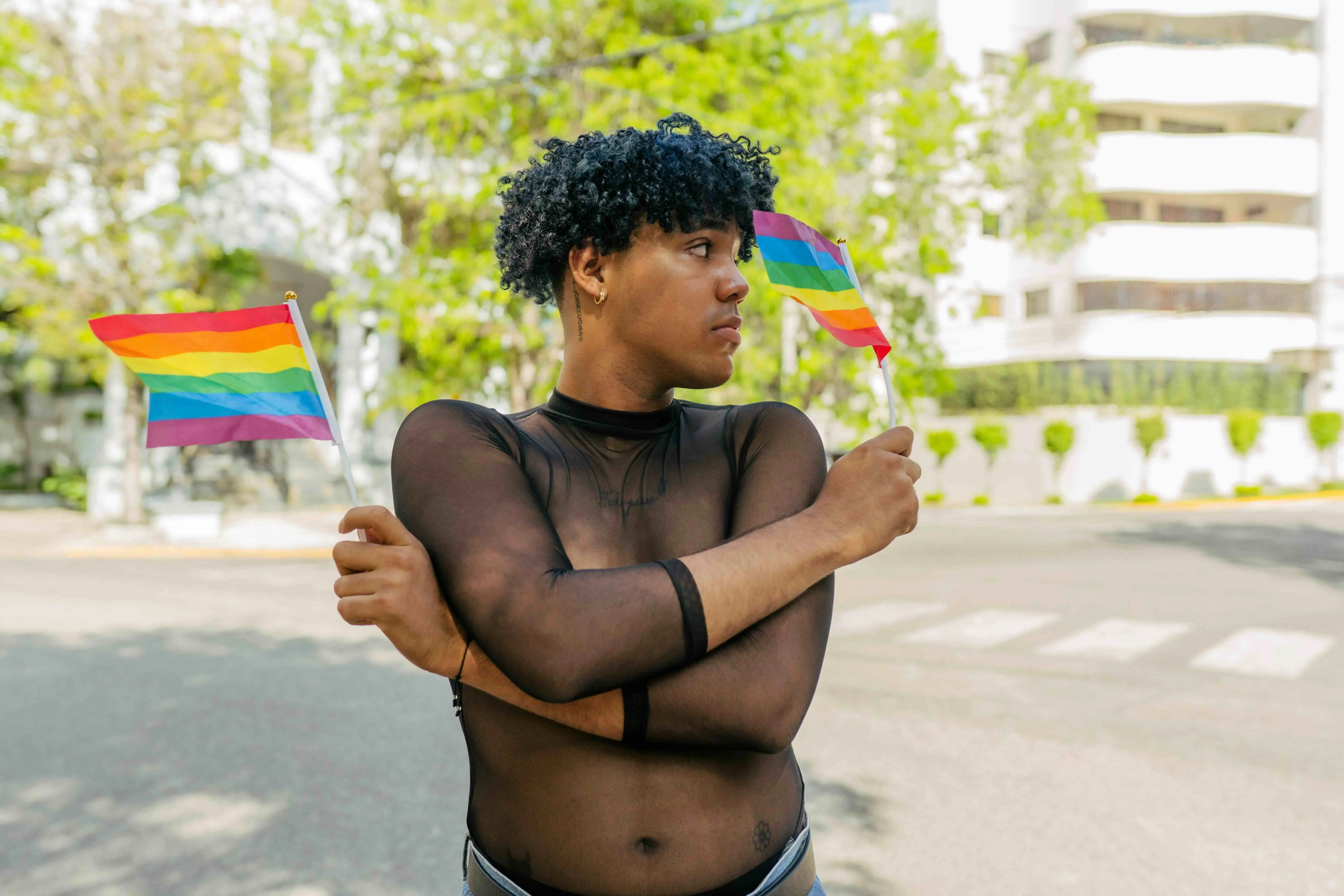 A queer person holding two queer flags to depict the struggles of being a queer late bloomer and coming out later in life, and dealing with late-life queerness India