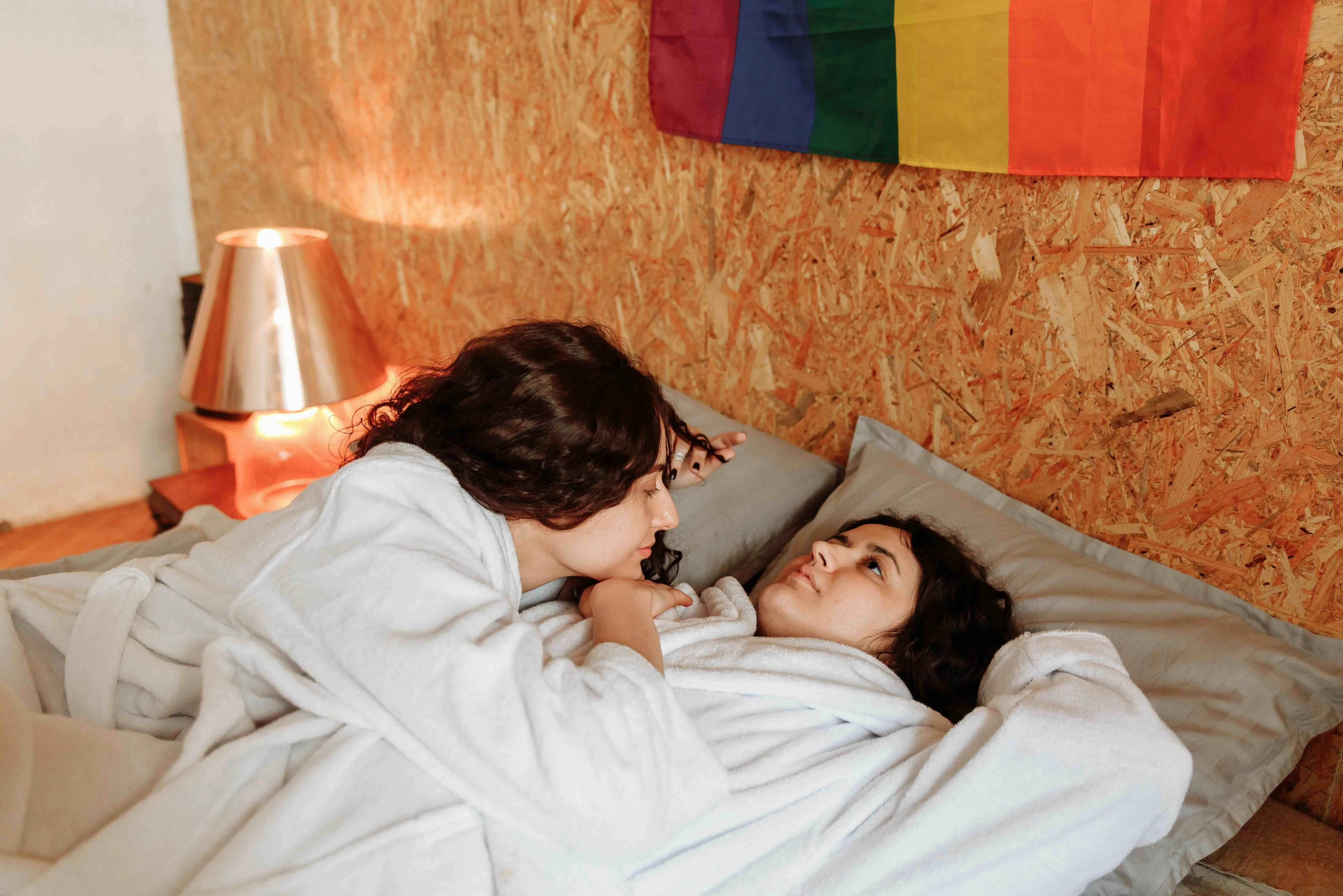 Two women, a queer couple, lie in bed to show how queer late bloomer who are entering their first queer relationship in adulthood need to have conversations and communicate to normalise late-life queerness India
