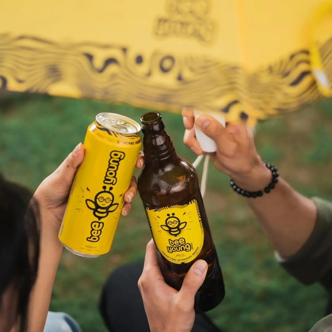 Three people holding up BeeYoung, one of the popular &nbsp;craft beer in India in the Indian beer industry and Indian microbreweries