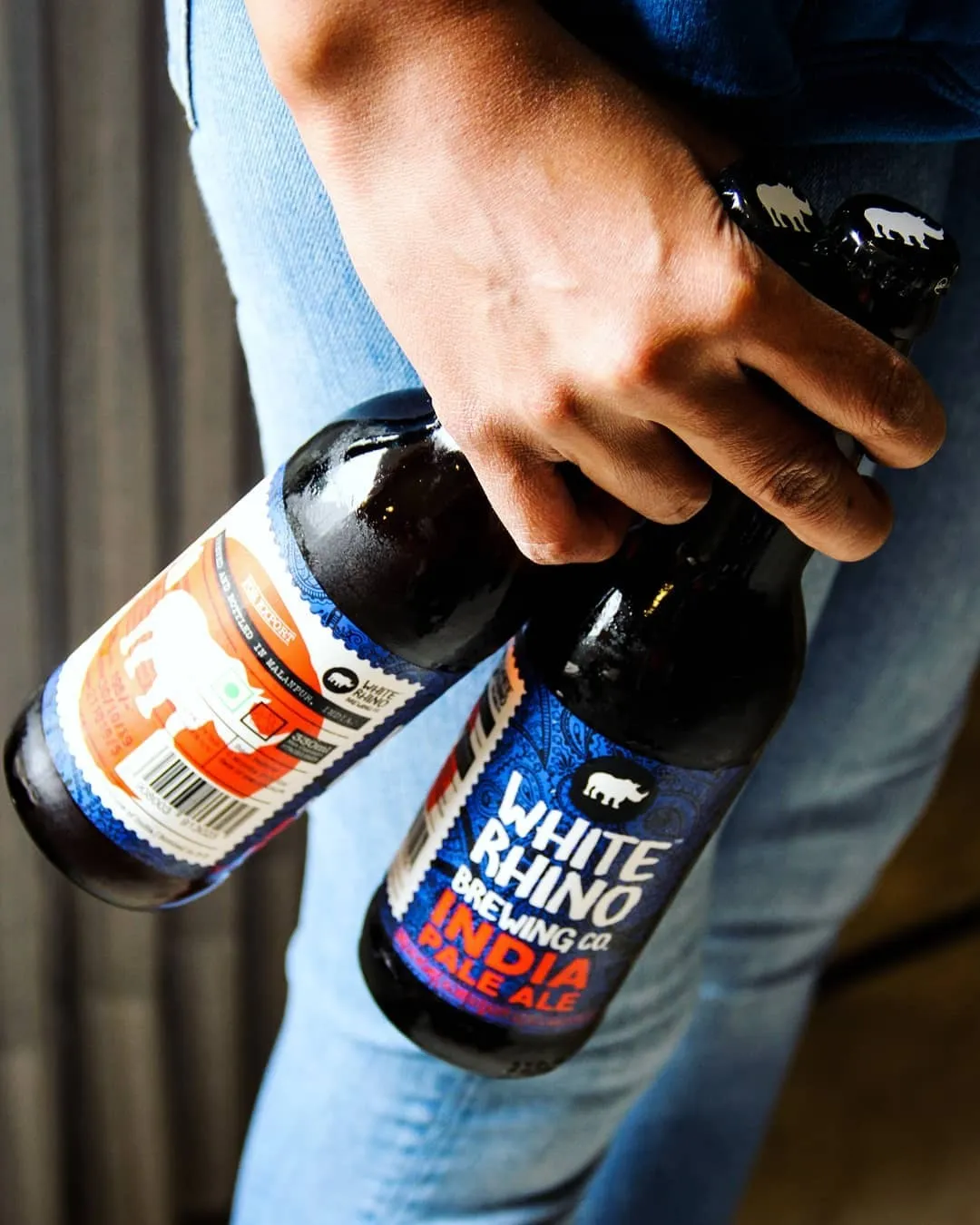 A person holding two bottles of White Rhino Brewing Co, a&nbsp;craft beer in India, one of the new beer brands India that are premium beer India