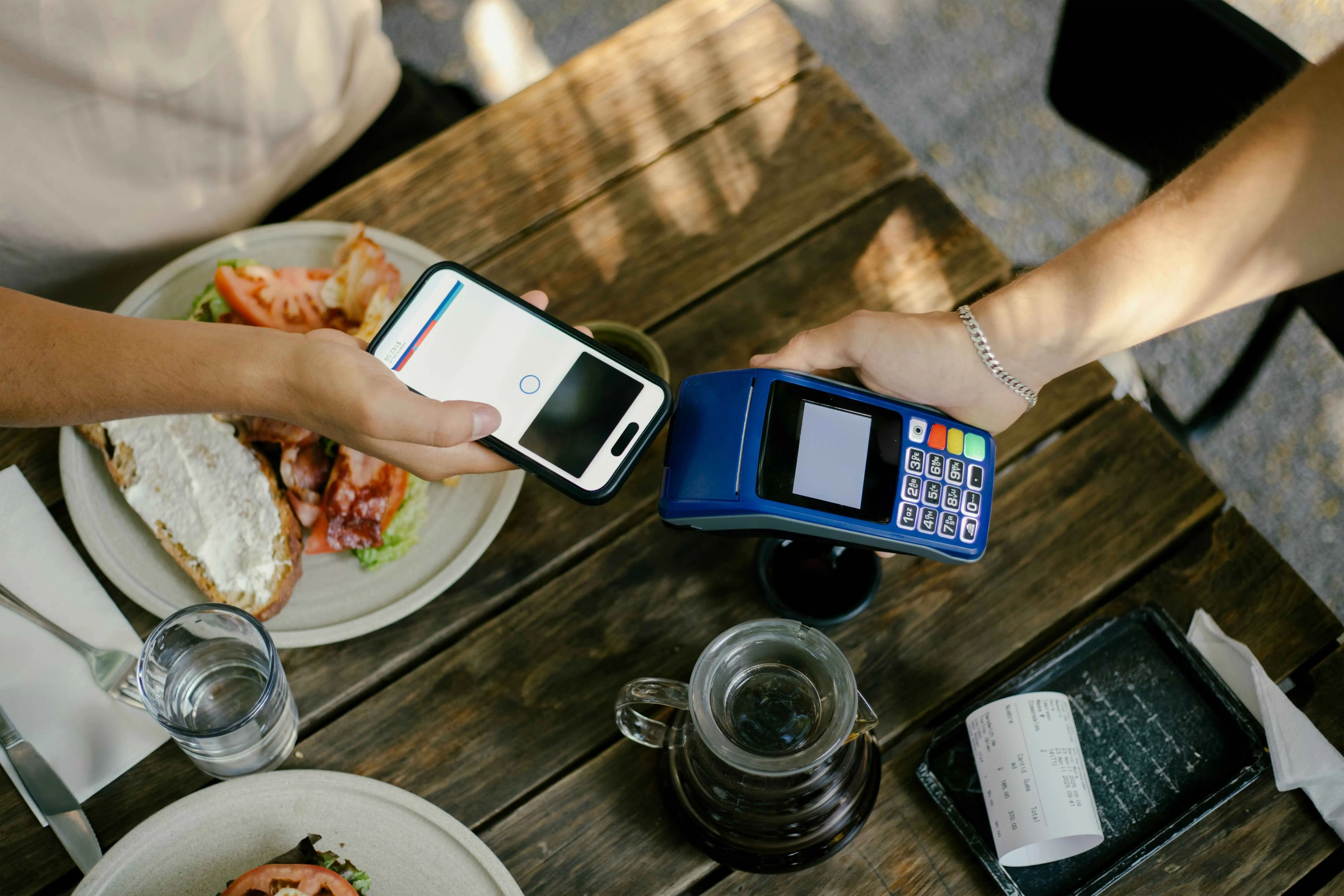 A flatly shot of a man paying off a bill at a restaurant through his phone