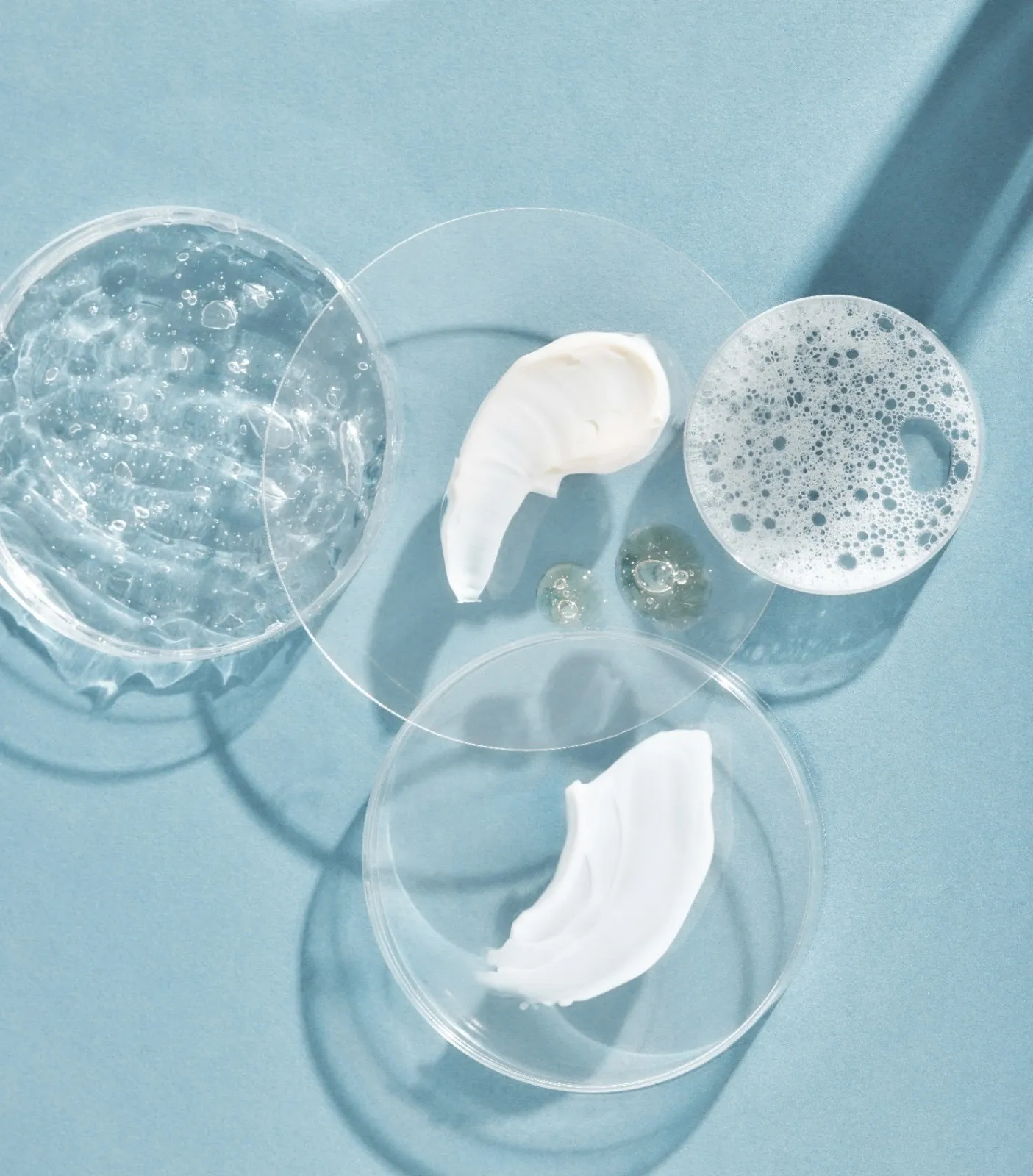 A picture of various texture smears of skincare products against a blue backdrop