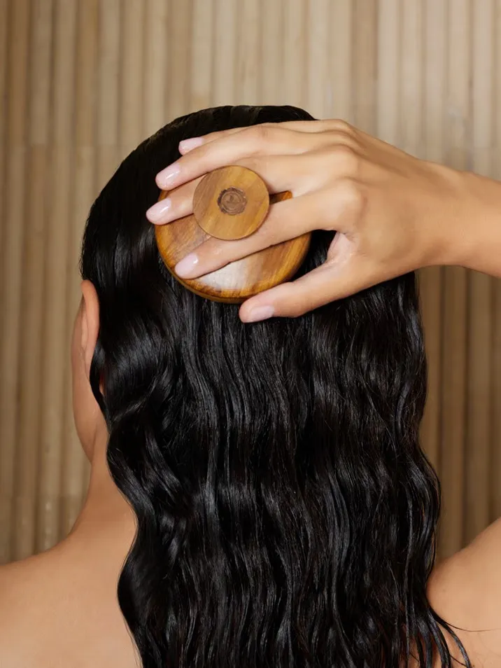 A woman applying the best hair oil and massaging with wooden massager