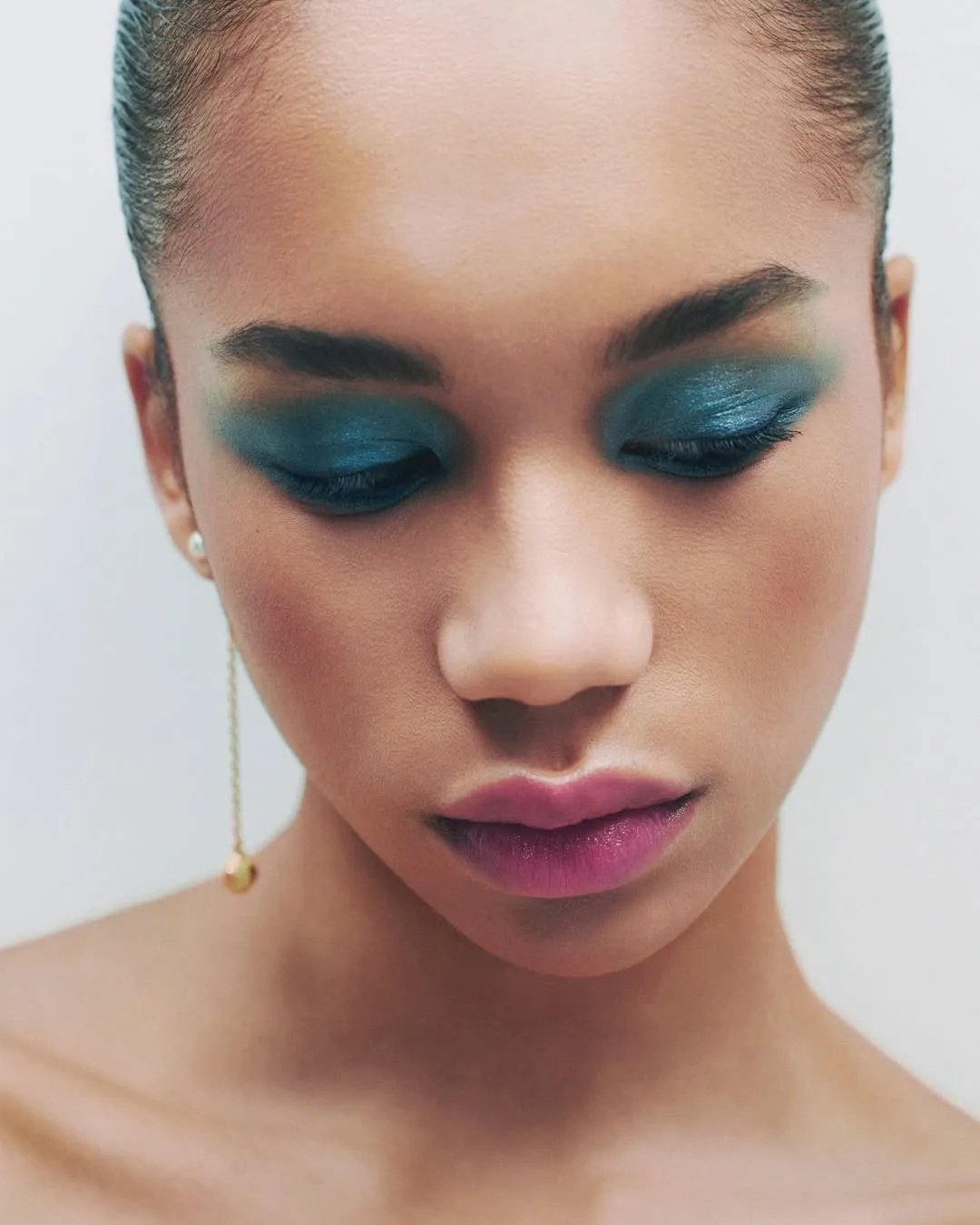 A picture of a female model with metallic blue eyeshadow and pink lips