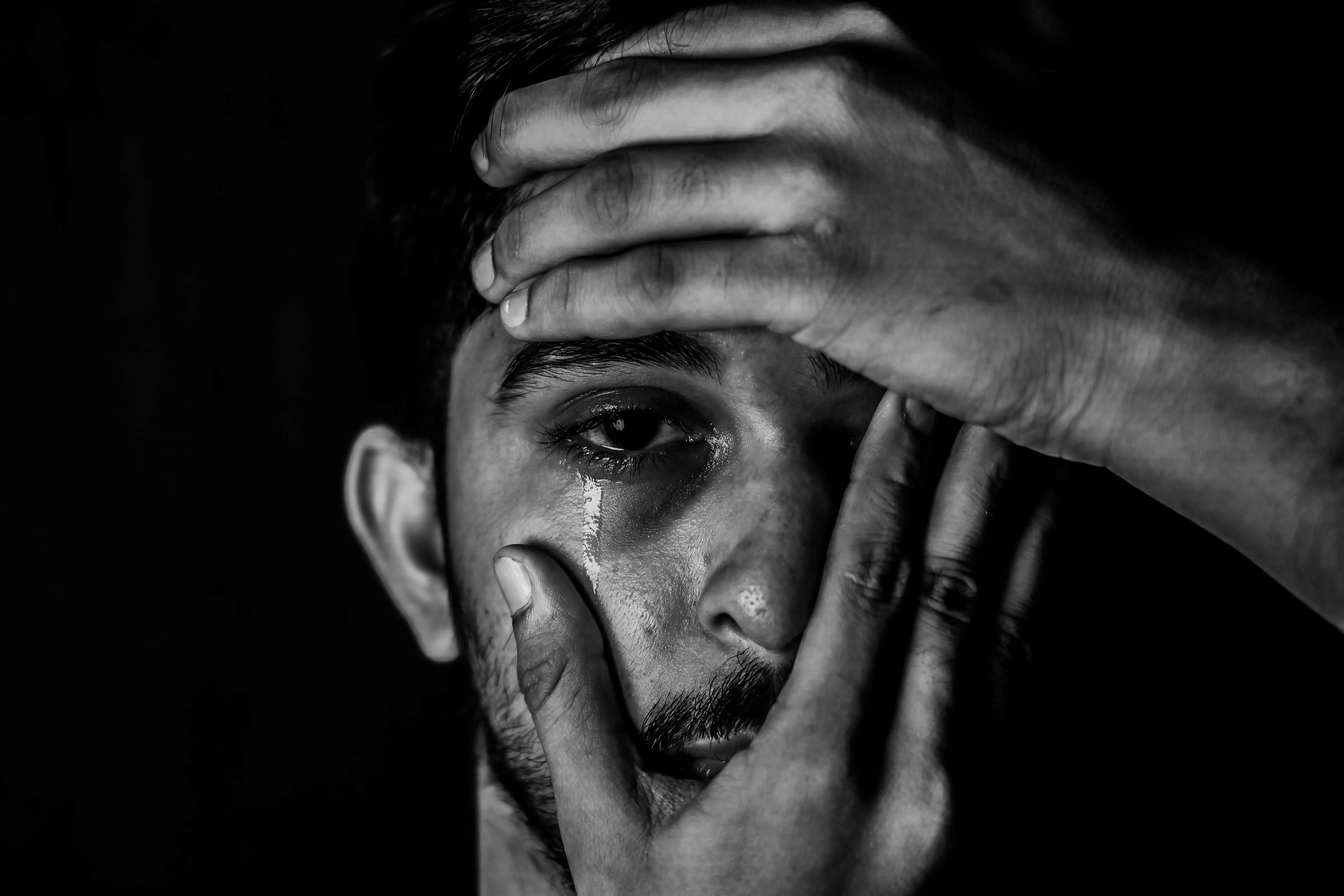 A picture of a man crying with hands covering his face to show how men miss out on the benefits of crying and collective crying sessions despite mental health awareness in India