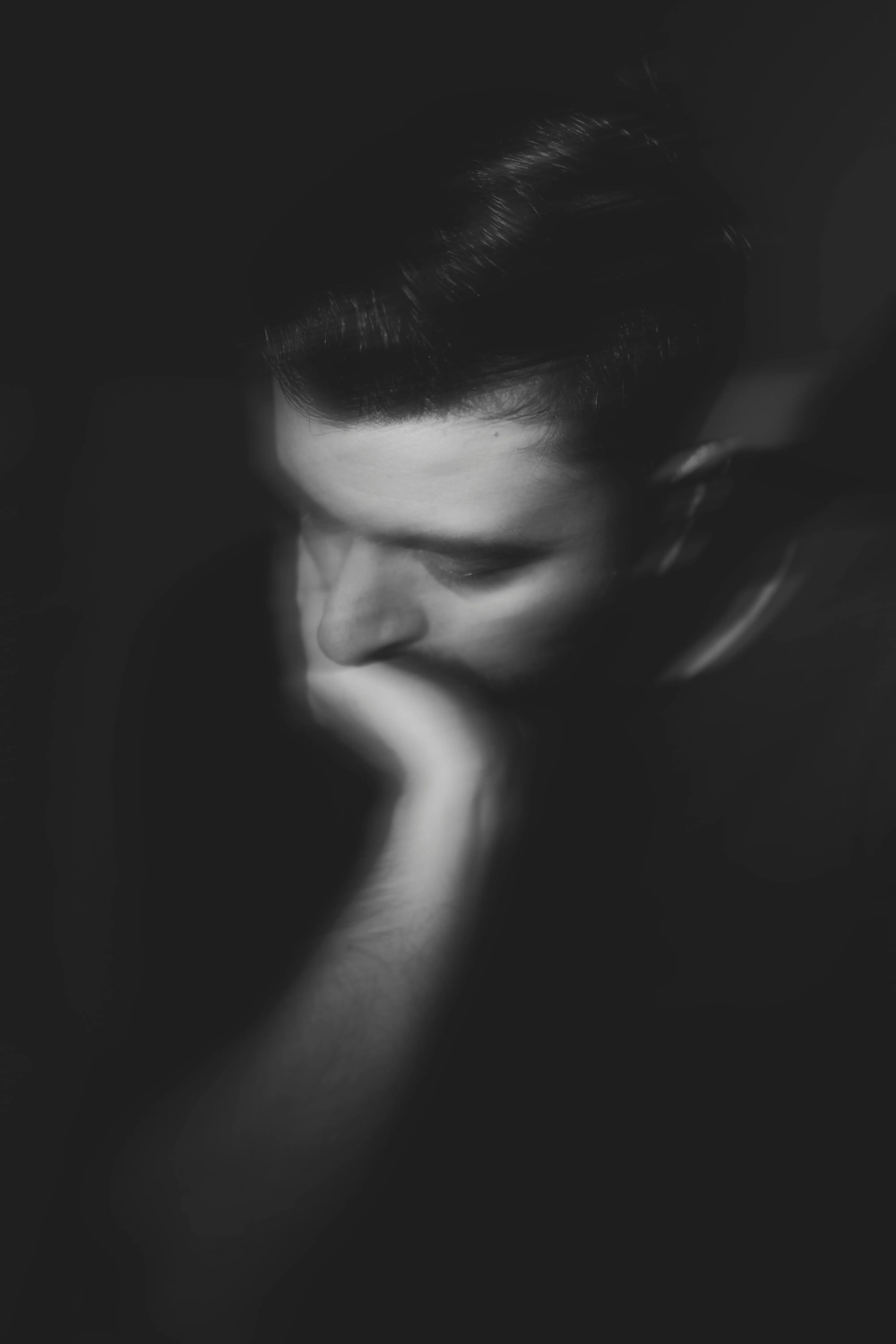 A black and white picture of a man trying not to cry to show how men are robbed of the benefits of crying and shamed for it, bringing no respite to urban loneliness in India or burnout in India via crying therapy in India