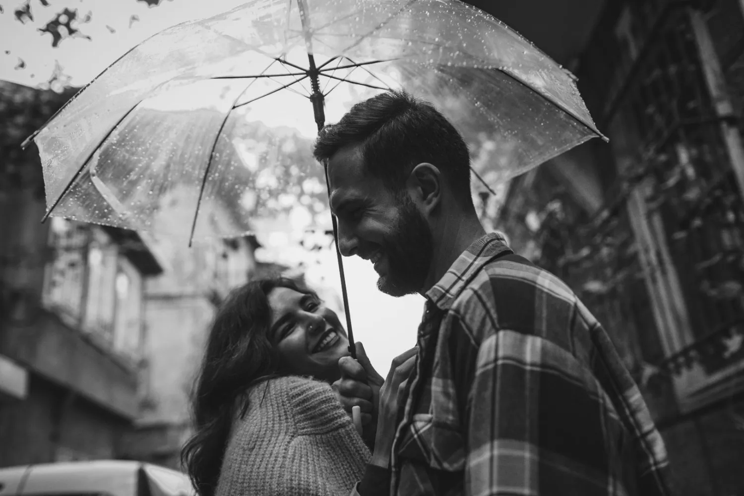 A black and white picture of a couple holding an umbrella to show how arranged marriage in India can be successful in India via matchmaking in India