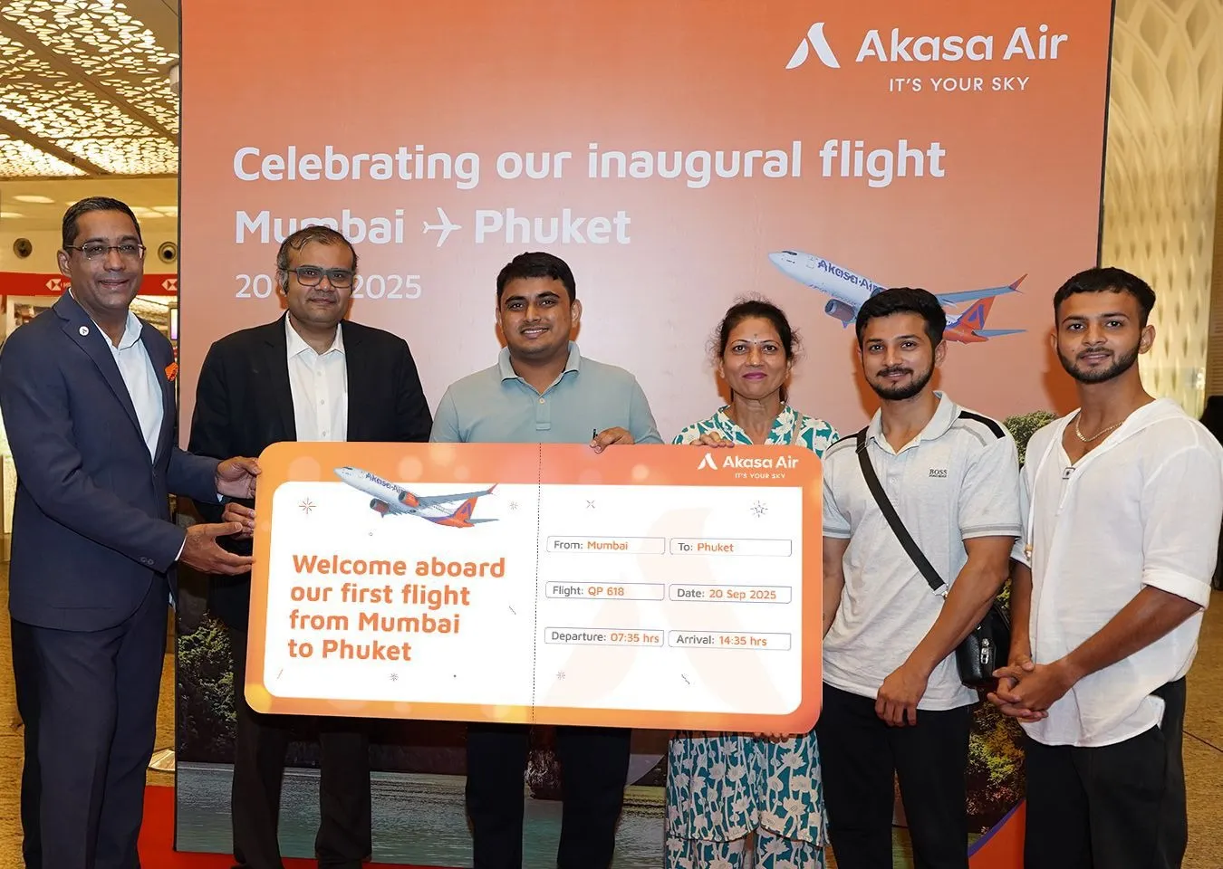 Belson Coutinho, Co-Founder and Chief Operating Officer, Akasa Air and Naarayan TV, Chief Marketing Officer, Akasa Air present the ceremonial boarding pass to the first passenger of Akasa Air's inaugural flight f