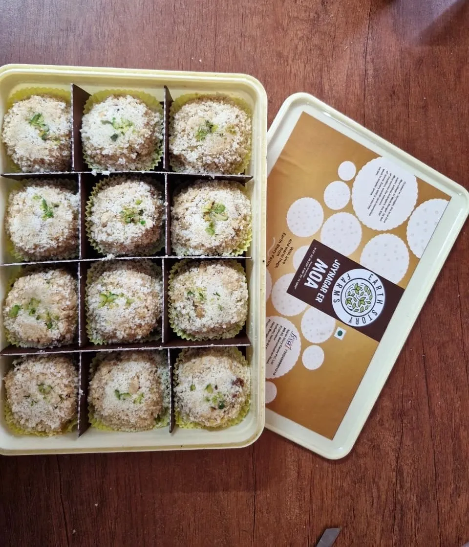An open box of Earth Story Farms Joynagar Er Moa, featuring 12 traditional Bengali sweet puffed rice balls topped with crushed pistachios