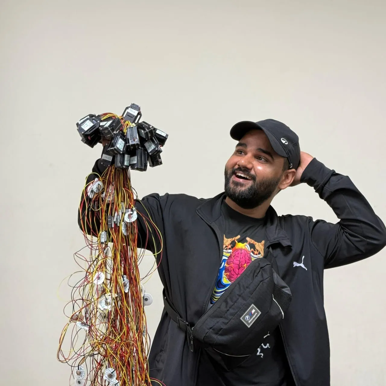 Delhi tech entrepreneur holding multiple neuroscience sensor modules with long electrode wires used for recording body signals