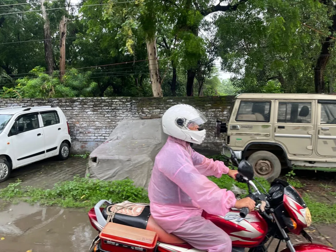 रेन कोट पहनकर डयूटी के लिए जाता कार्मिक