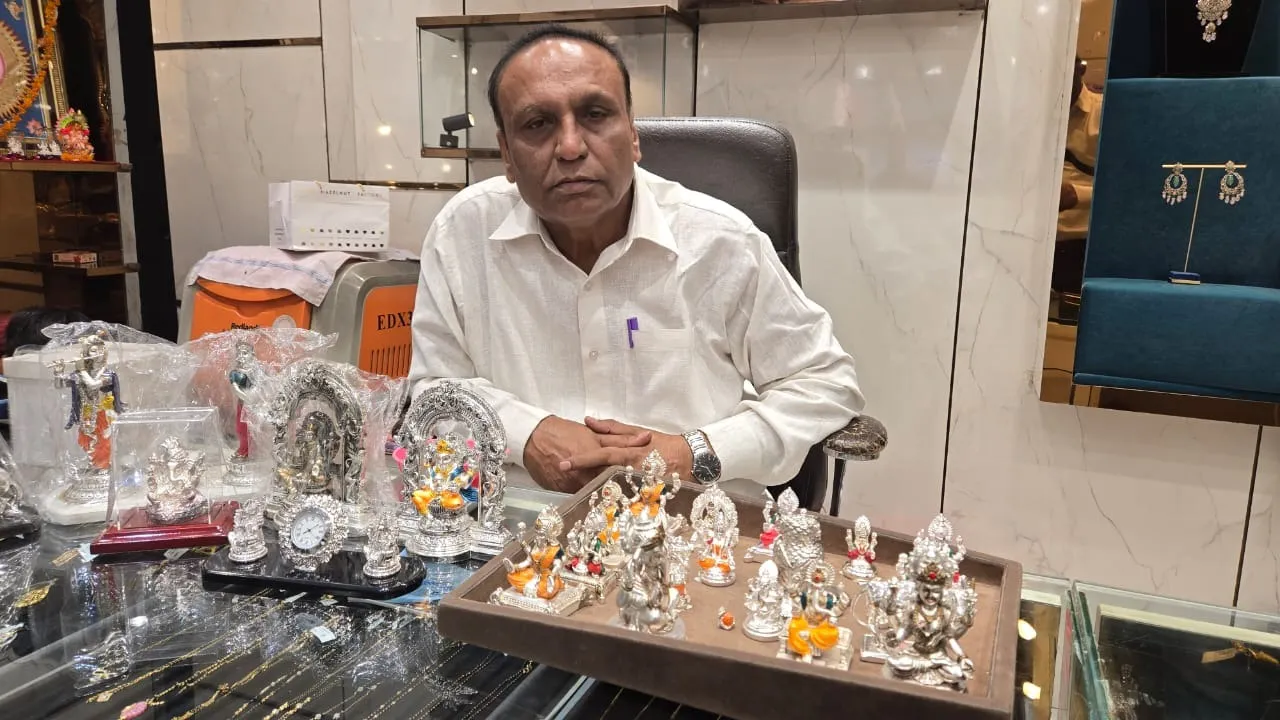 सदर बाजार में धनतेरस की पूर्व संध्या पर चांदी से बनी लक्ष्मी गणेश प्रतिमाओं को स्टाल पर सजाने के बाद उनके बारे में जानकारी देते विनोद सर्राफ