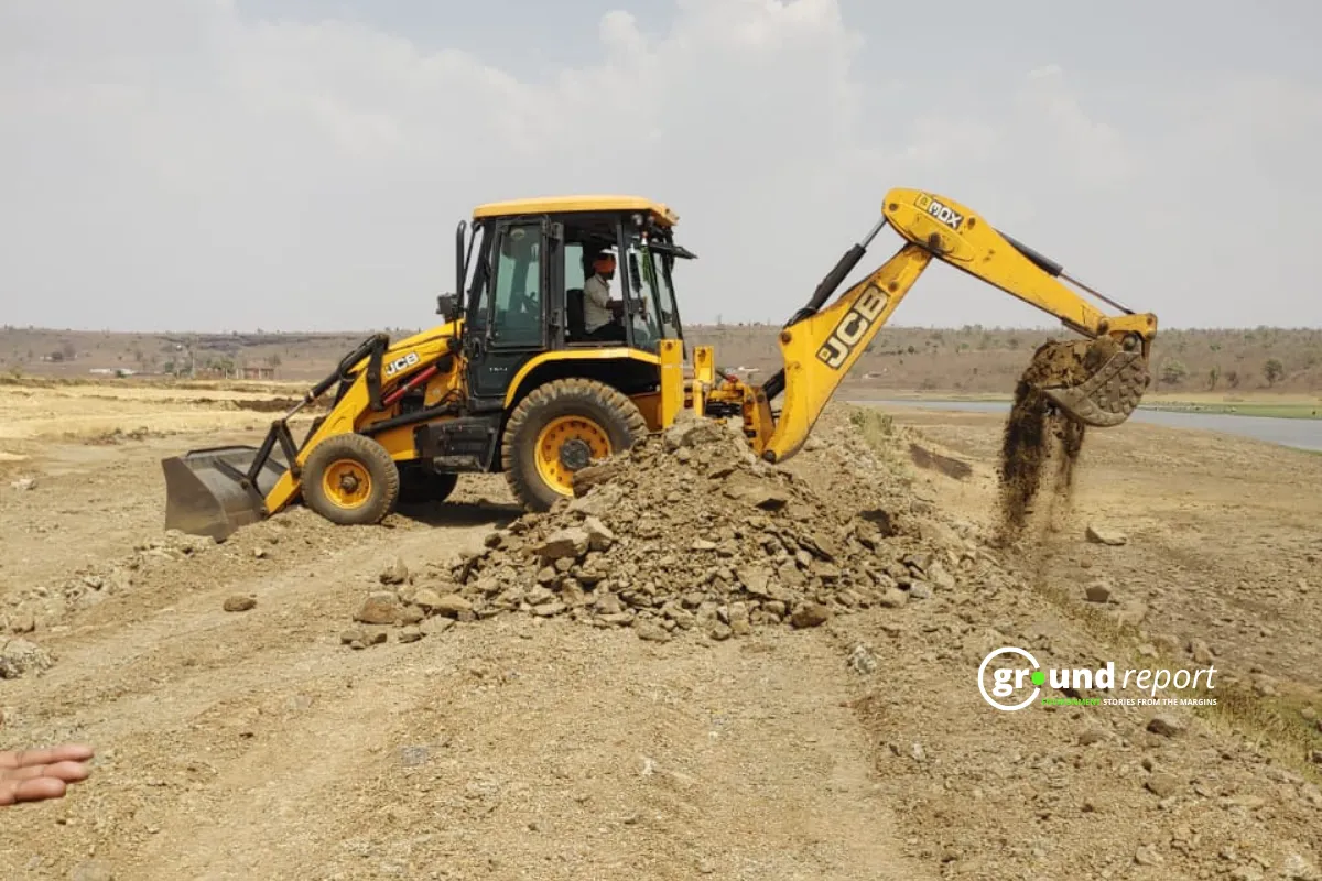 Huzur SDM Vinod Sonkia uses JCB to clear illegally dumped soil from Kerwa Dam’s full tank level in Mahuakheda village.