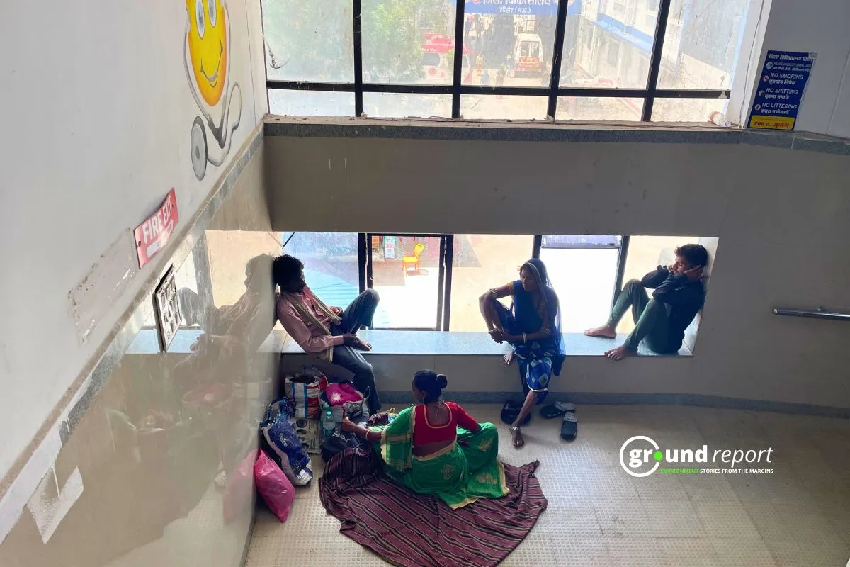 Outside the children's ward of Sehore Hospital, patients and their relatives are sitting near the window to escape the heat.