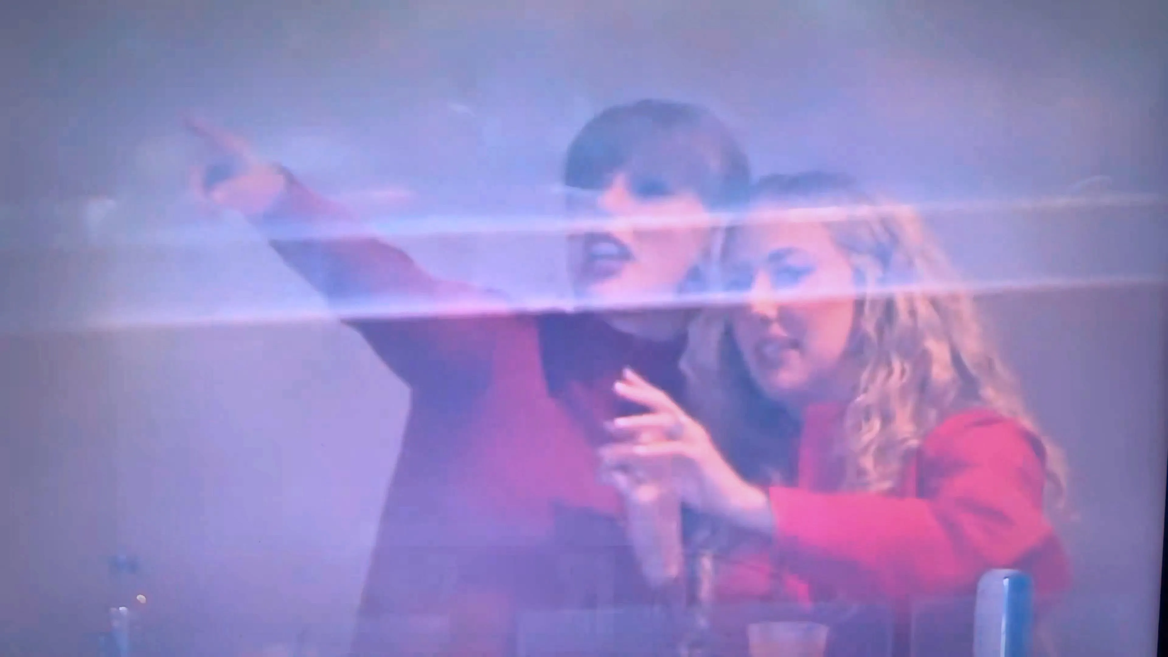 Taylor Swift pointing and Brittany Mahomes watching a game.