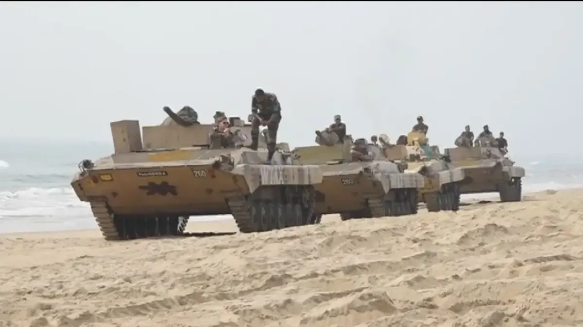 Battle tanks await their turn to demonstrate their power along the ocean's edge