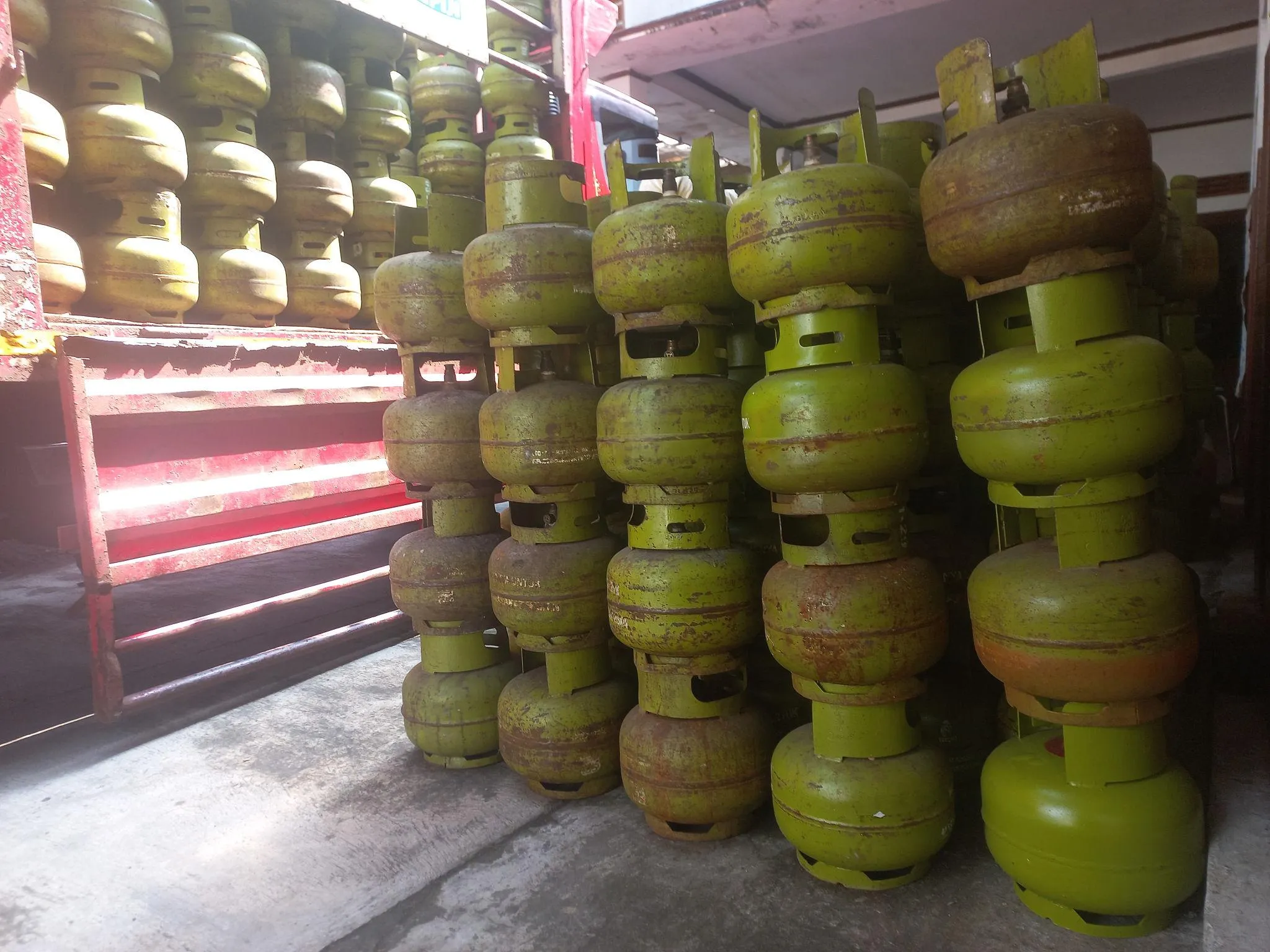 A stack of green LPG,Liquefied Petroleum Gas cylinders. These cylinders typically contain 3 kg of LPG and are widely used for cooking in households.