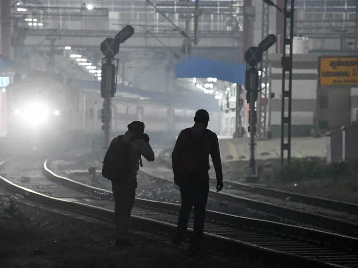 उत्तर प्रदेश: प्रयागराज में घने कोहरे के बीच दो शख्स रेलवे ट्रैक पार करते हुए।