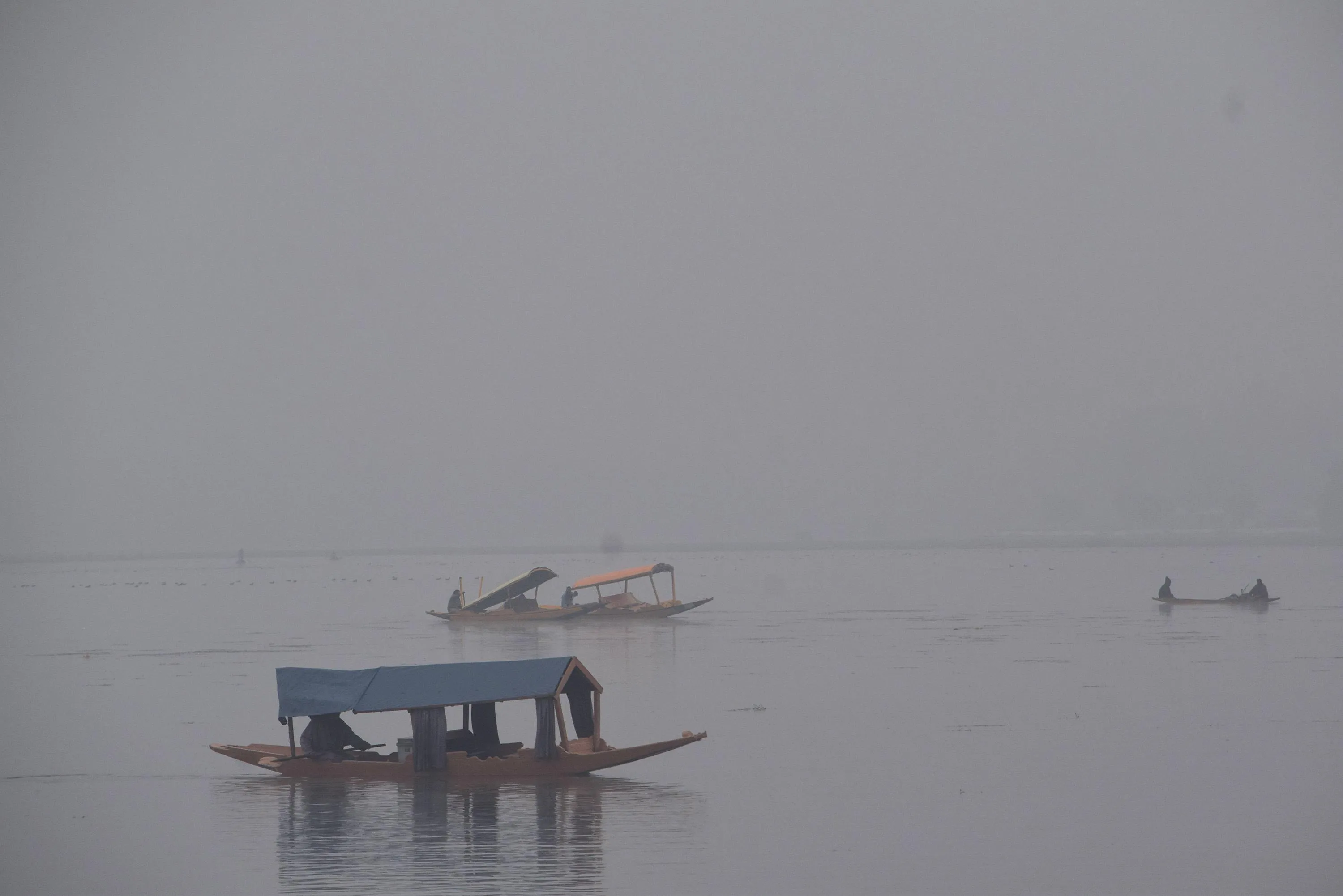 जम्मू-कश्मीर: श्रीनगर में सर्द सुबह, घने कोहरे के बीच नाविक शिकारा चलाते हुए।