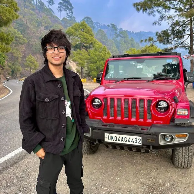 This may contain: a man standing next to a red jeep