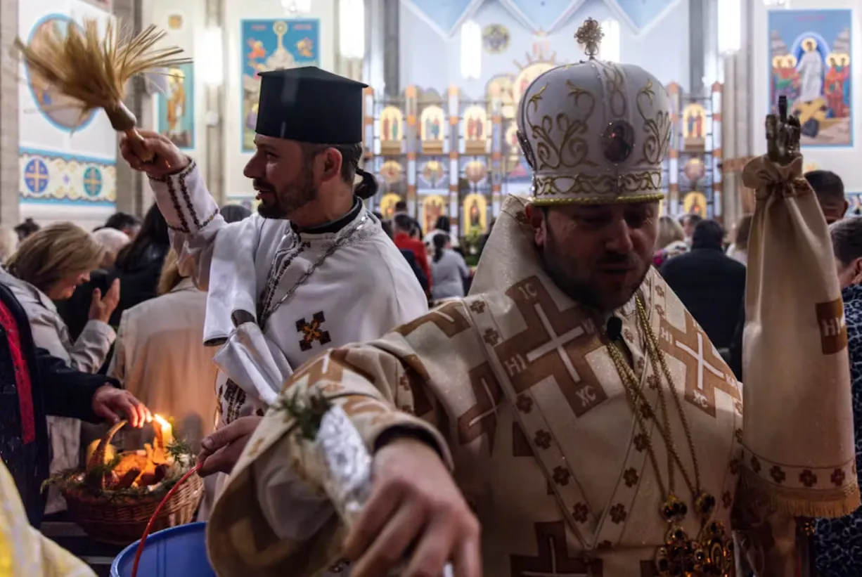 Parish Andriy Mykytyuk (left) and Cardinal Mykola Bychok bless worshippers during a Ukrainian Catholic Easter celebration in Melbourne, April 2023. Diego Fedele/AAP